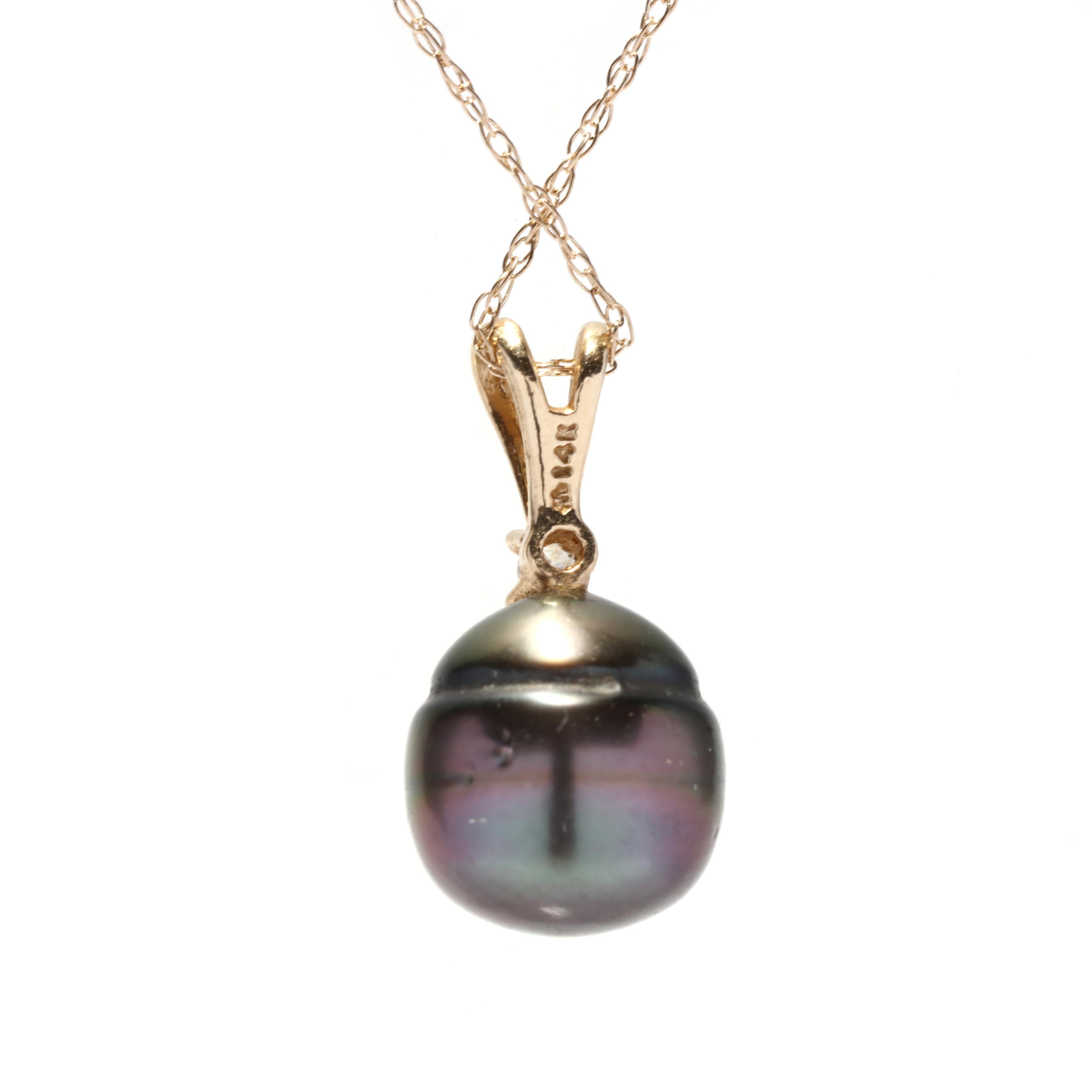 A 10 karat yellow gold Tahitian pearl and diamond pendant necklace. This simple necklace features a oval bead shape Tahitian pearl set below a round brilliant cut diamond weighing approximately .02 carat and suspended from a thin rope