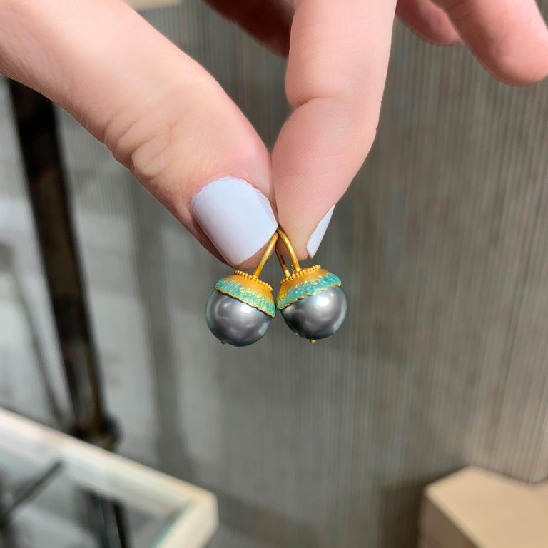 One of a Kind Earrings hand-fabricated in Belgium by acclaimed jewelry maker Eva Steinberg showcasing a stunning matched pair of lustrous 10mm round peacock blue Tahitian pearls set in 21k yellow gold and embellished with a turquoise bluish green