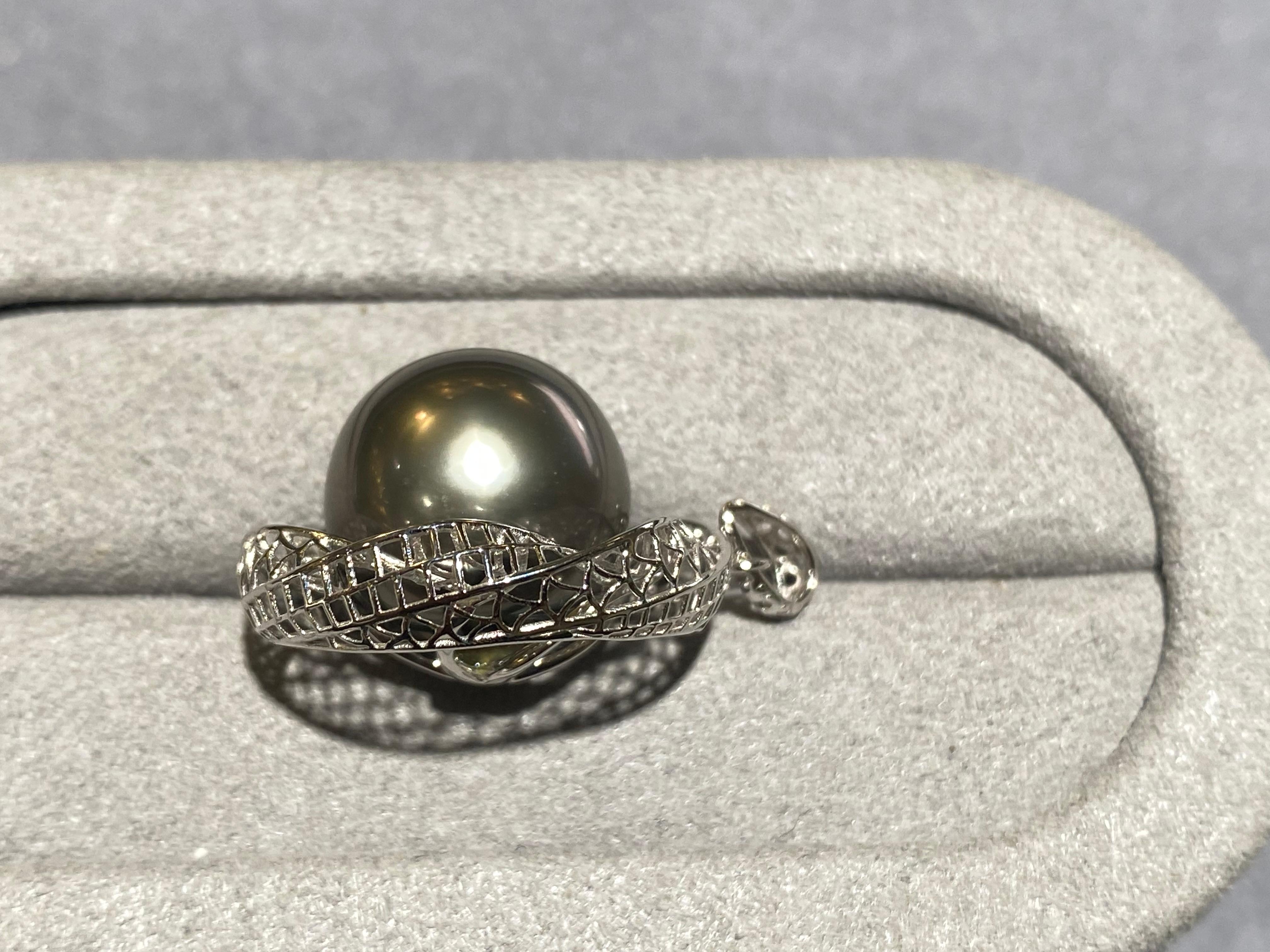 A round 13.6 mm tahitian pearl pendant in 18k white gold. The pearl is set in the middle of a round 18k white gold mesh which you can see through. It is a very simple design and is perfect for everyday wear. The pearl is grey in colour with