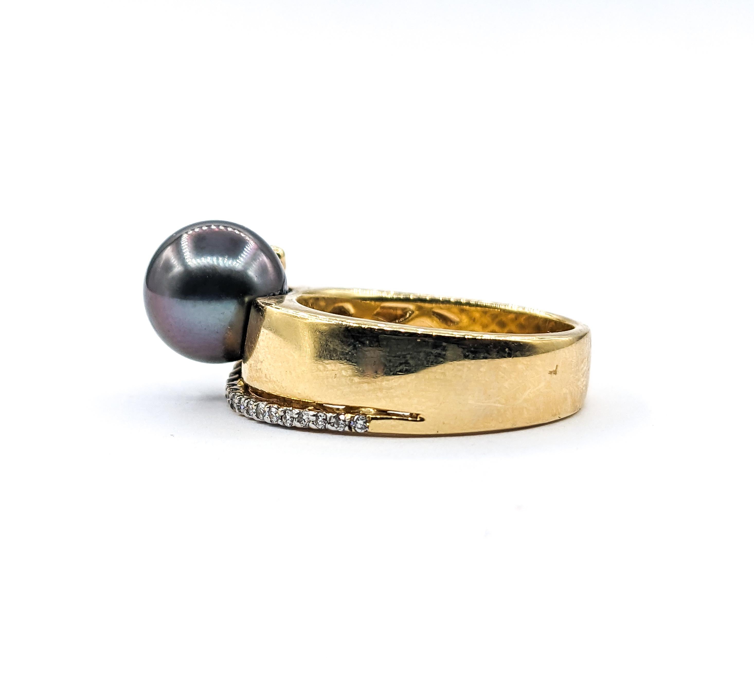 Cette bague sculpturale met en valeur une perle de Tahiti de 9,5 mm aux accents de paon, nichée dans une rangée de diamants ronds de taille brillant totalisant environ 0,10 carat. Les diamants se courbent gracieusement le long du bracelet