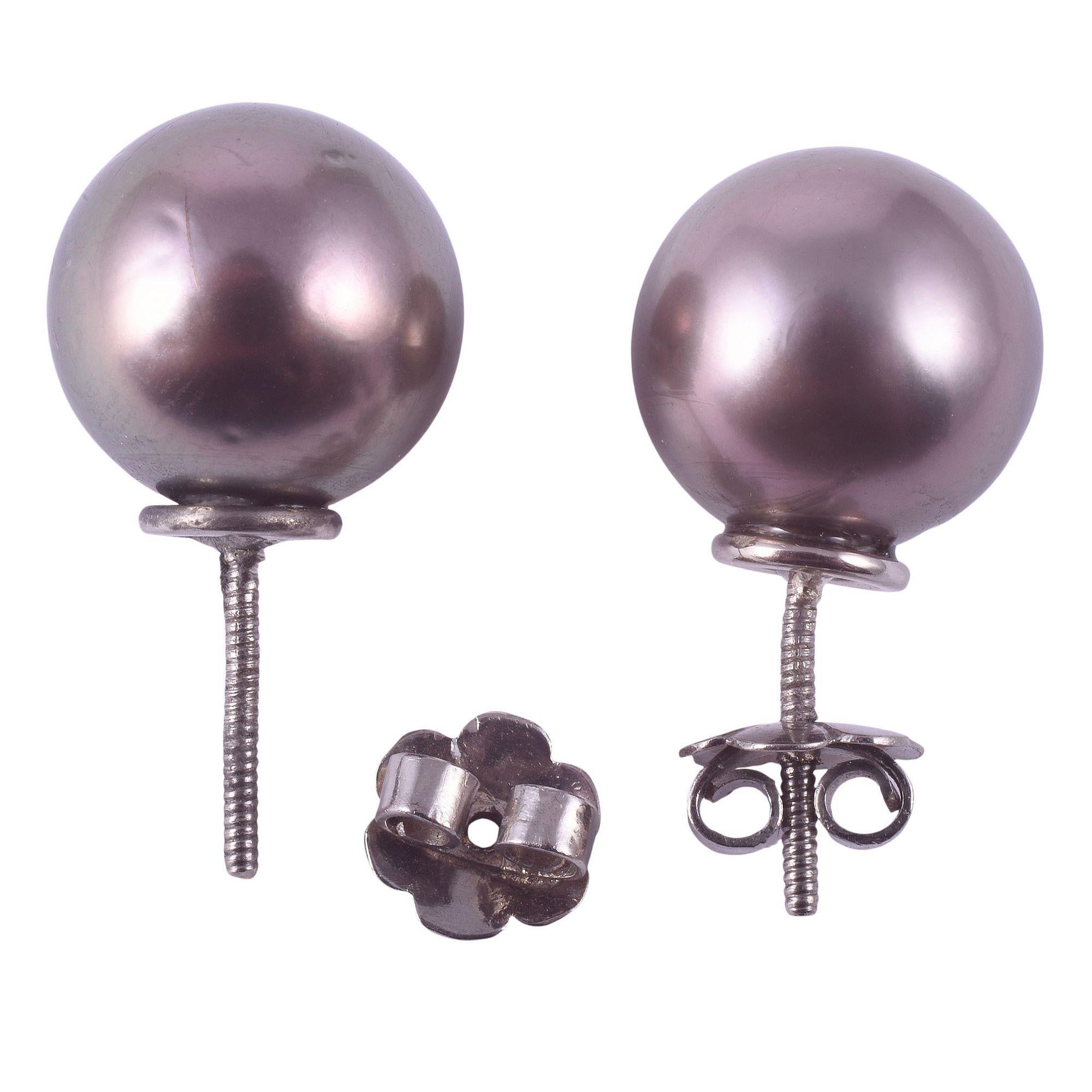 Estate Tahitian pearl stud earrings. These stud earrings are crafted in 14 karat gold and feature 13.5-13.6mm Tahitian pearls that are dark gray in color with green and rose overtones and light blemishes. The earrings are screwbacks. [KIMH 594]