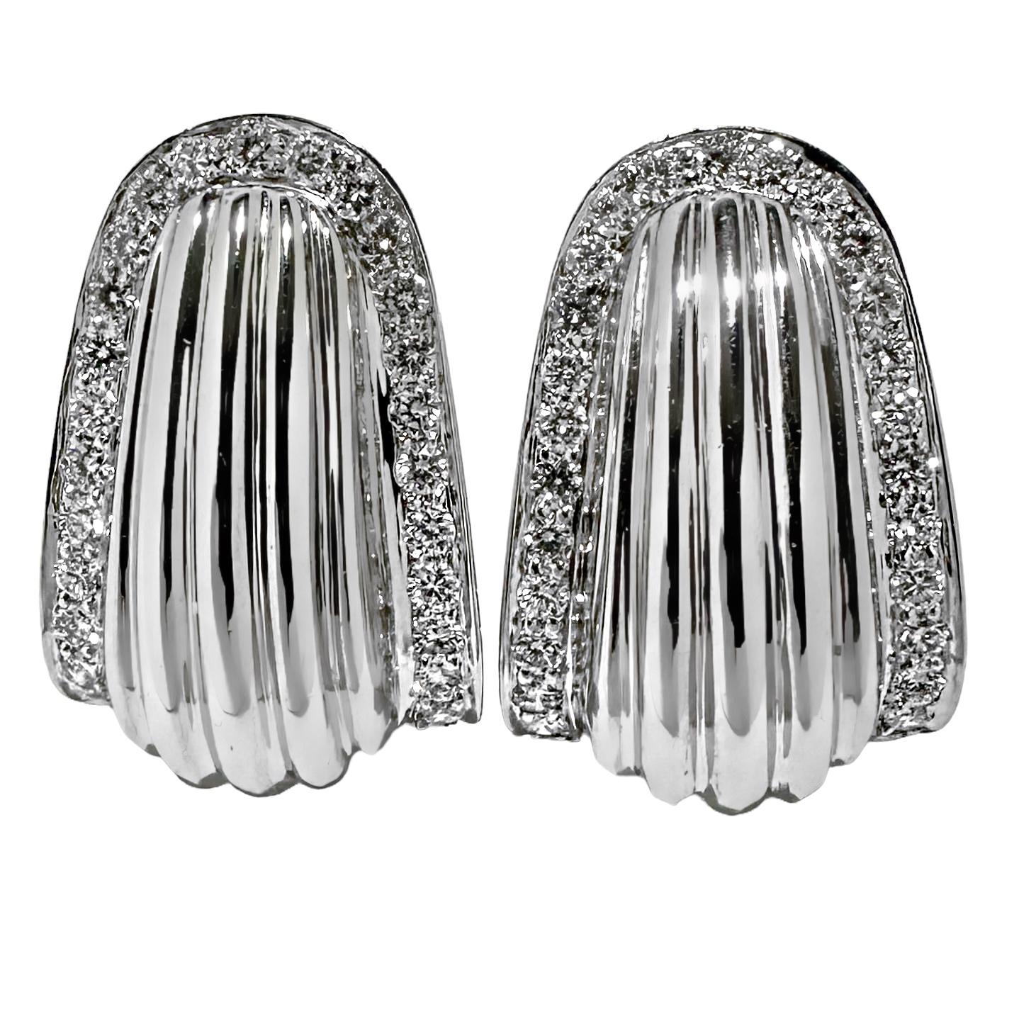 A smart looking pair of 18K white gold earrings, with a designer look, centered around a high polished, fluted design. A row of pave' set diamonds moves up one side and down the other in a horseshoe shape, adding brilliance while outlining the