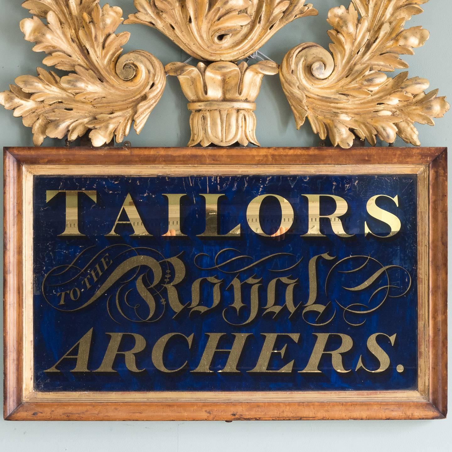 Victorian reverse painted advertisement, 'Tailors to the Royal Archers', the verre églomisé gilt serif lettering on a royal blue ground, set within bird’s eye maple frame with gilt slip surmounted by gilt foliate cresting.

The Royal Company of