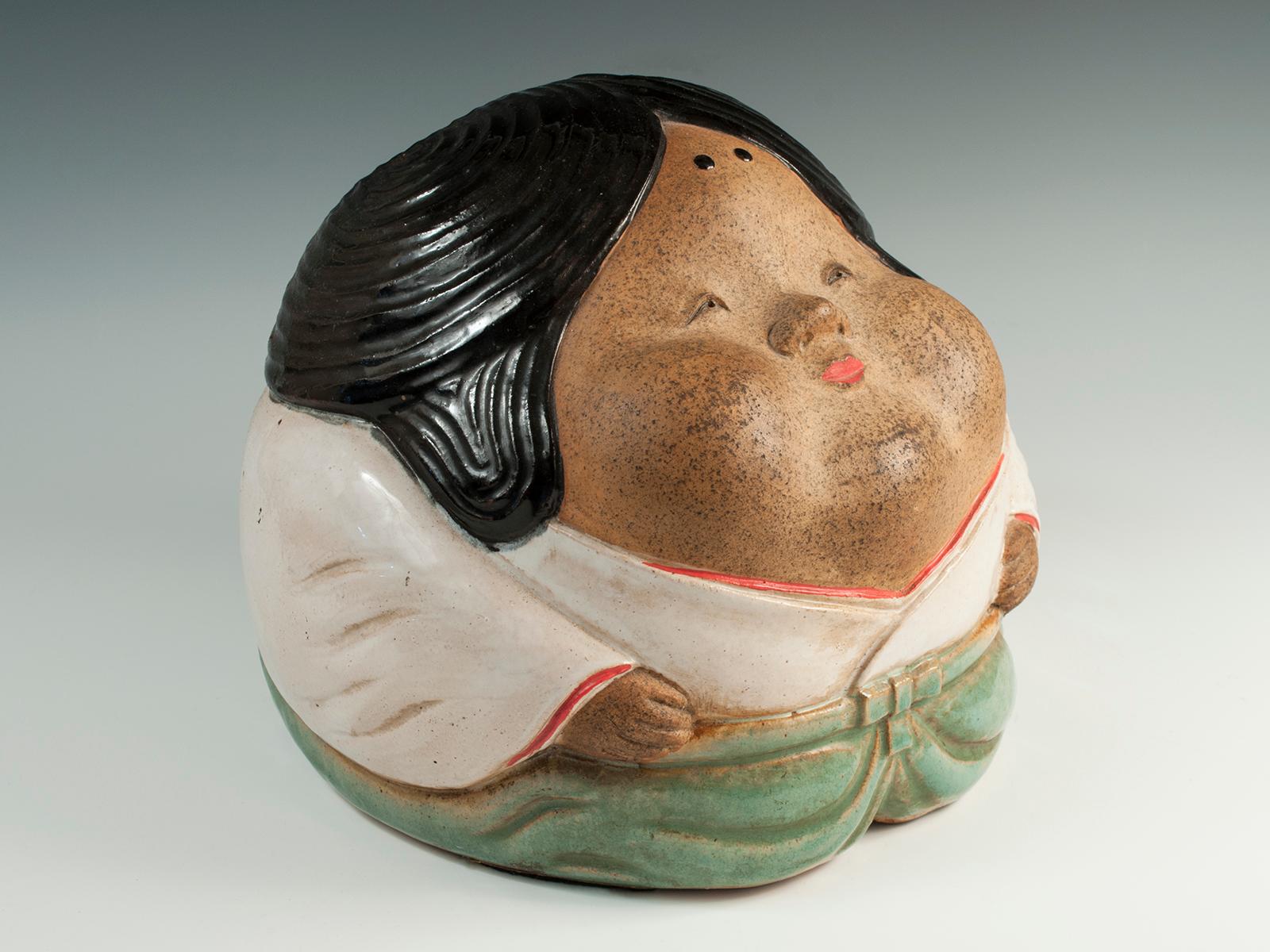 Offered by Zena Kruzick
Taisho Period Shigaraki Okame Hand Warmer, Japan

This charming Japanese stoneware hand warmer is in the form of the Noh theater character known as Okame (aka Otafuku). Okame is known as the goddess of mirth, while her