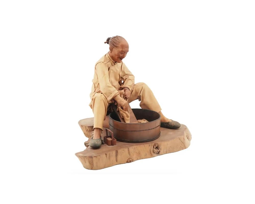 Liu Miao Chan, Taiwanese, born 1946, a carved wood sculpture predicting a man dressed in leather and washing clothes. Comes with the certificate of authenticity. Numbered 4 of 10. Dated 1989. Liu Miao Chan was declared a national living treasure by