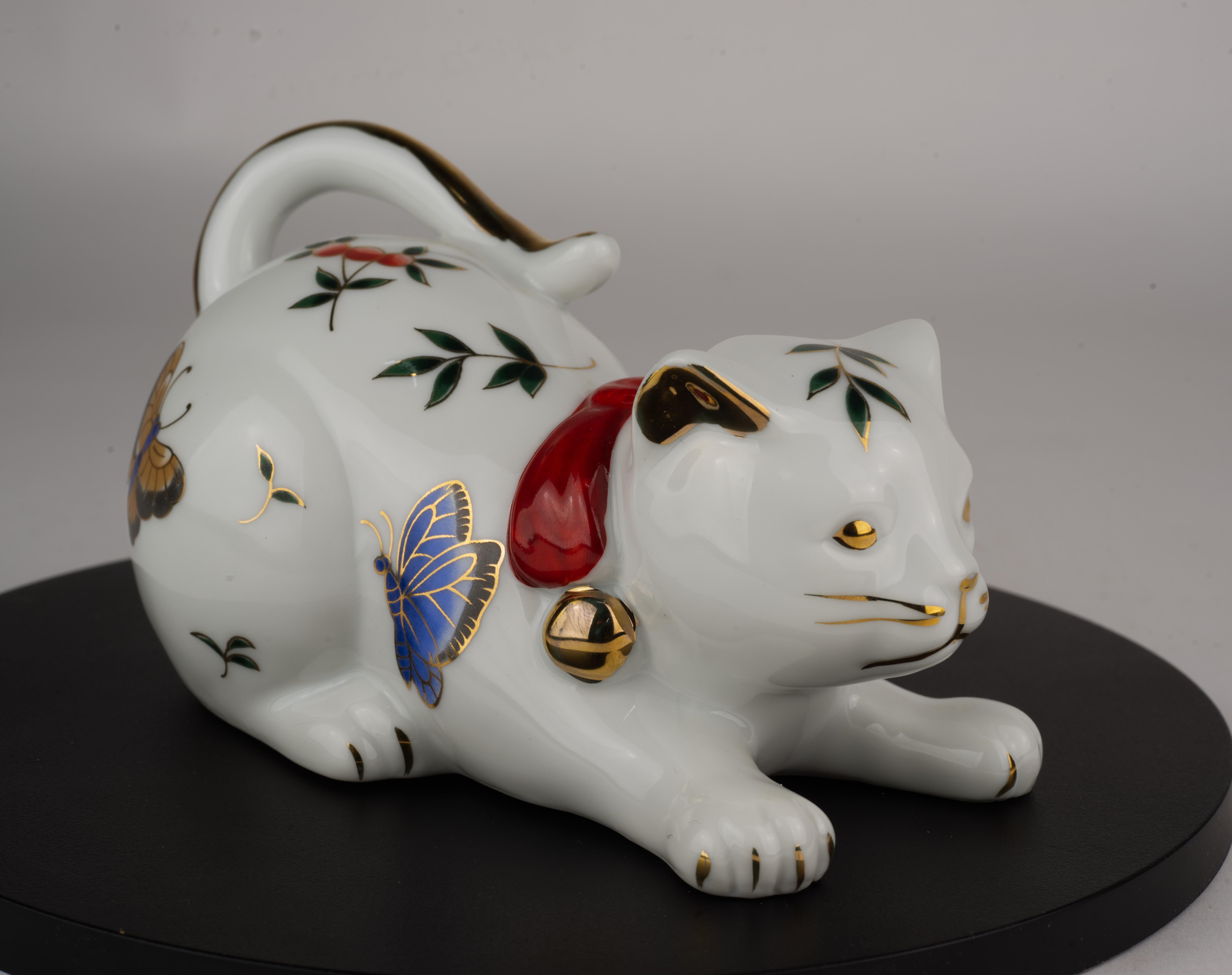 Rare porcelain figurine of a playing cat is hand decorated with butterflies and leaves designs and gold accents. It is unusual to find a playing cat figurine; most Takahashi cats are depicted sleeping with their heads on their paws, tails folded