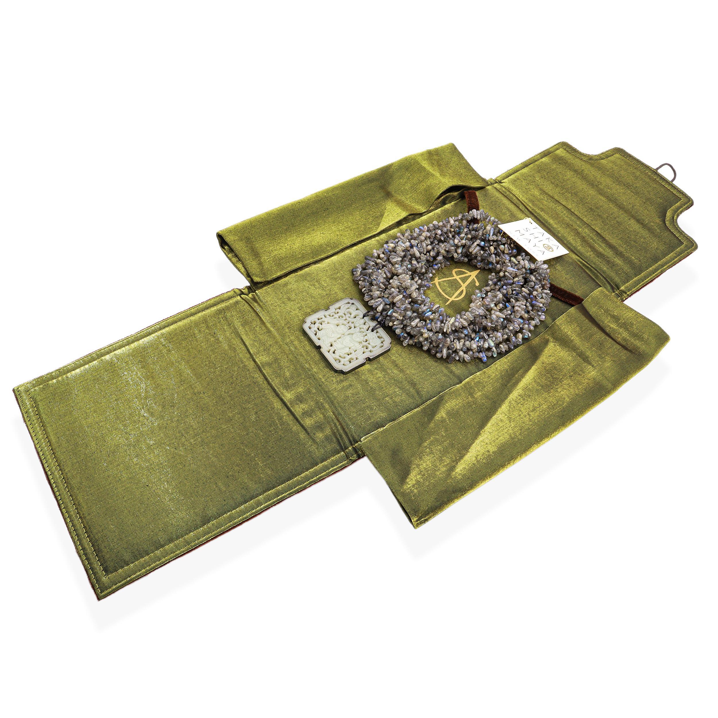 Collana di Takashi Maya &New York, con scaglie di labradorite a più fili dalla texture ricca e con iridescenze naturali blu e oro. I fili si uniscono per mostrare un grande ciondolo a placca di giada intagliata che raffigura figure tradizionali e