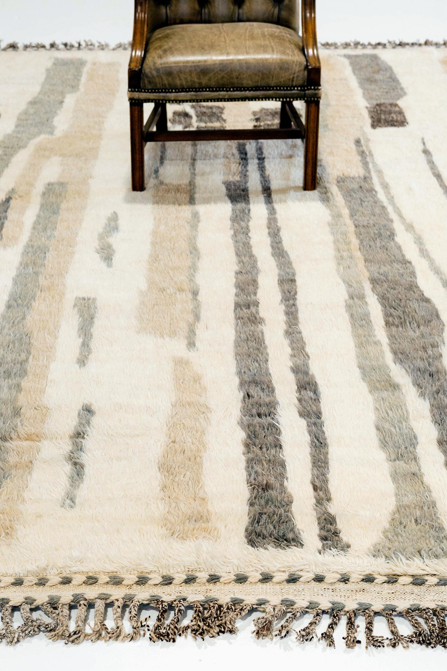 Talassemtane' is a beautifully textured rug with irregular motifs inspired from the Atlas Mountains of Morocco. Smoke, tan, and charcoal colors surrounded by the perfect white shag work cohesively to make for a great contemporary interpretation for