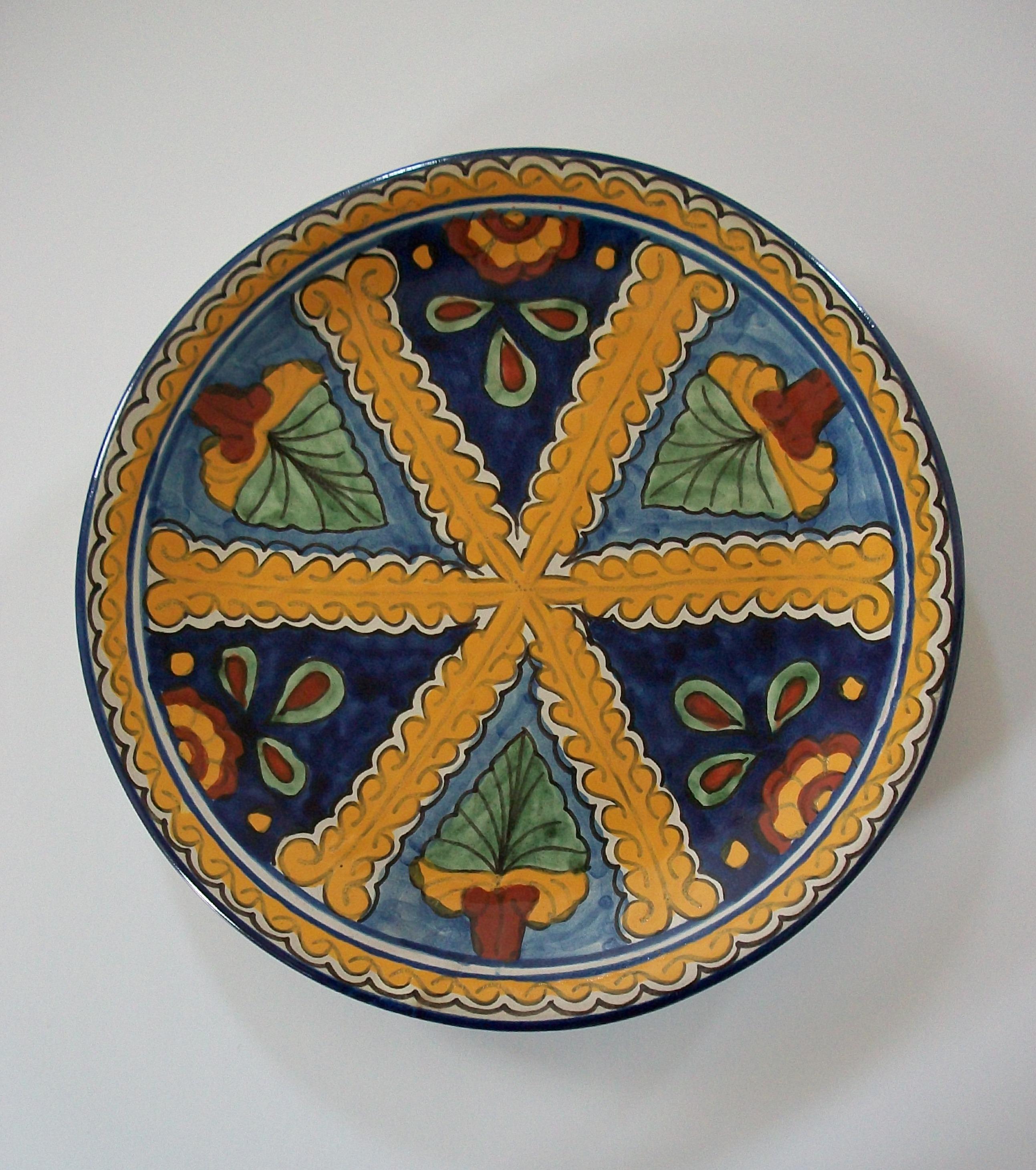Chargeur ou assiette mexicaine en terre cuite émaillée Talavera - grand format - fait à la main - présentant des feuilles et des fleurs peintes à la main à l'intérieur d'une bordure élaborée avec des tourbillons - deux trous sur le bord arrière pour