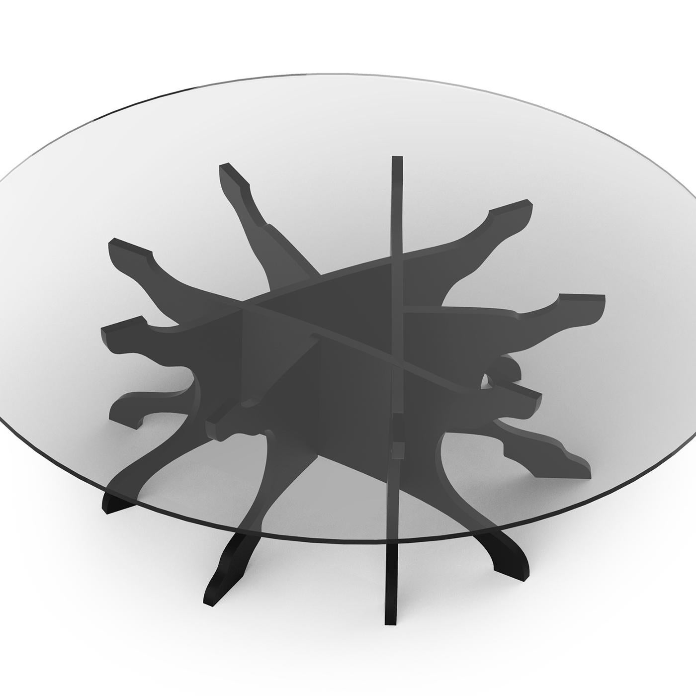 Round coffee table featuring a modern and refined design. The original base is a true sculpture, made of molded plywood birch, painted in matt black. The elegant round top, with a diameter of 100 cm, is in extra-clear tempered glass. The Tale table