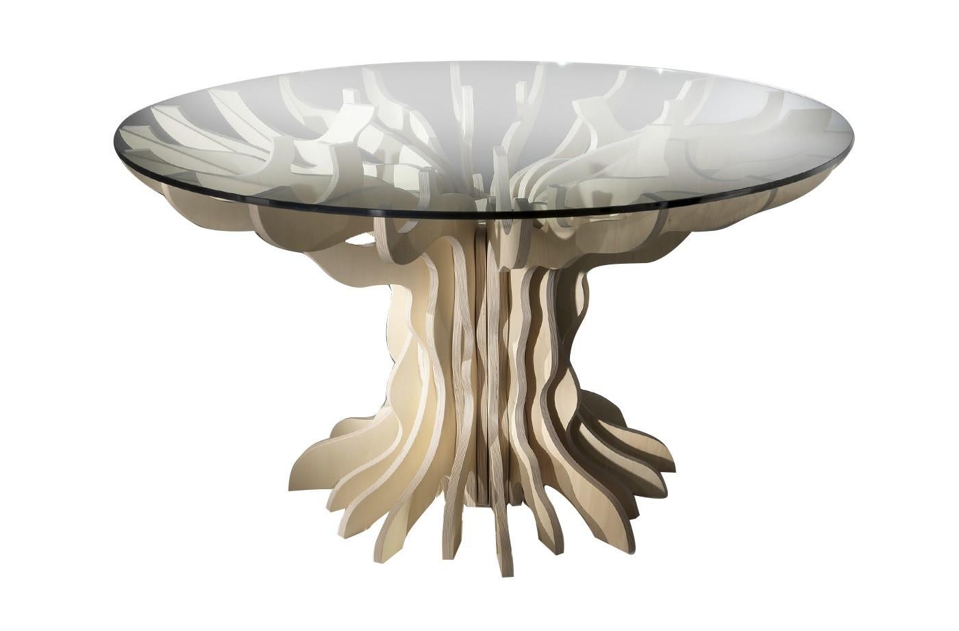 This extraordinary table features a unique design. Its structure is crafted from individual pieces of natural birch wood arranged in a circle forming a tree-like shape. The round top is in tempered glass. The striking contrast between the natural