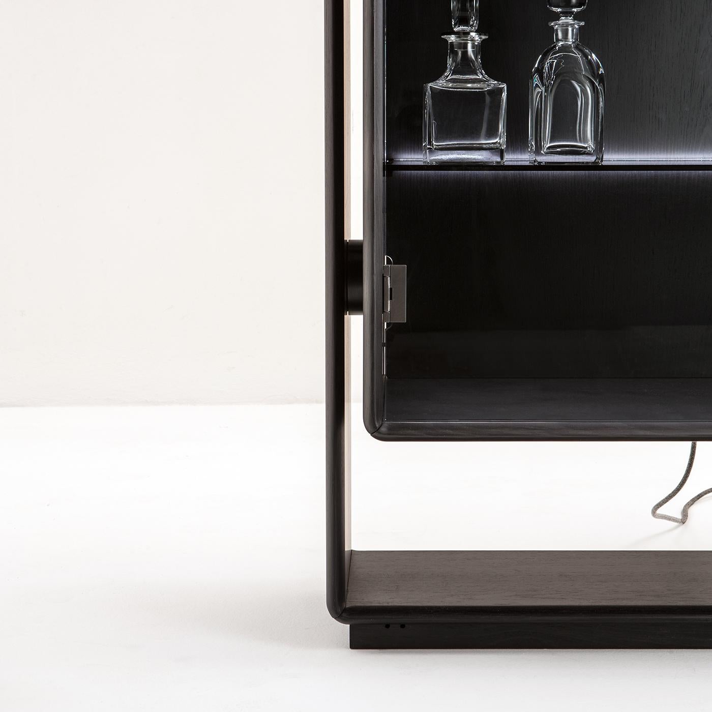 Questa credenza ha un forte impatto visivo in cui tecnica e stile si fondono in un sapiente equilibrio di spazi positivi e negativi con profondità alternate. L'interno è dotato di illuminazione a LED e di ripiani in vetro e legno, mentre le porte in