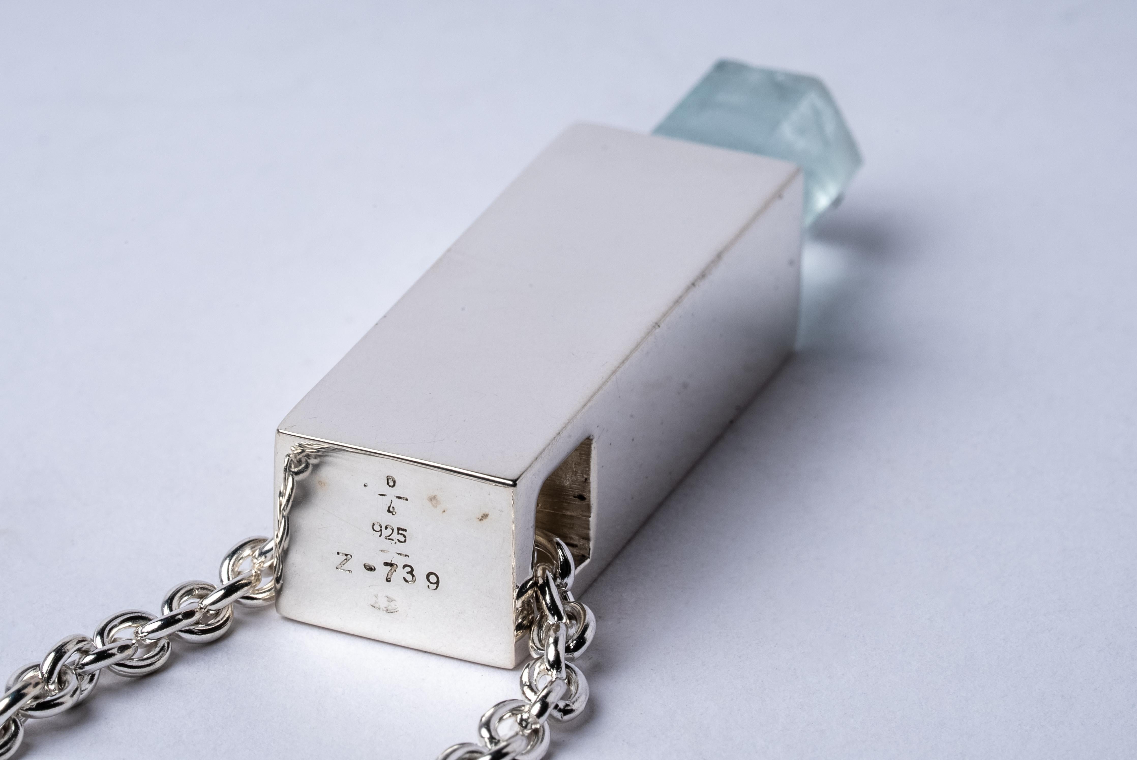 Necklace in the cuboid shape made in polished sterling silver and a rough of aquamarine. The Talisman series is an exploration into the power of natural crystals. The crystals used in these pieces are discovered through adventure and are hand