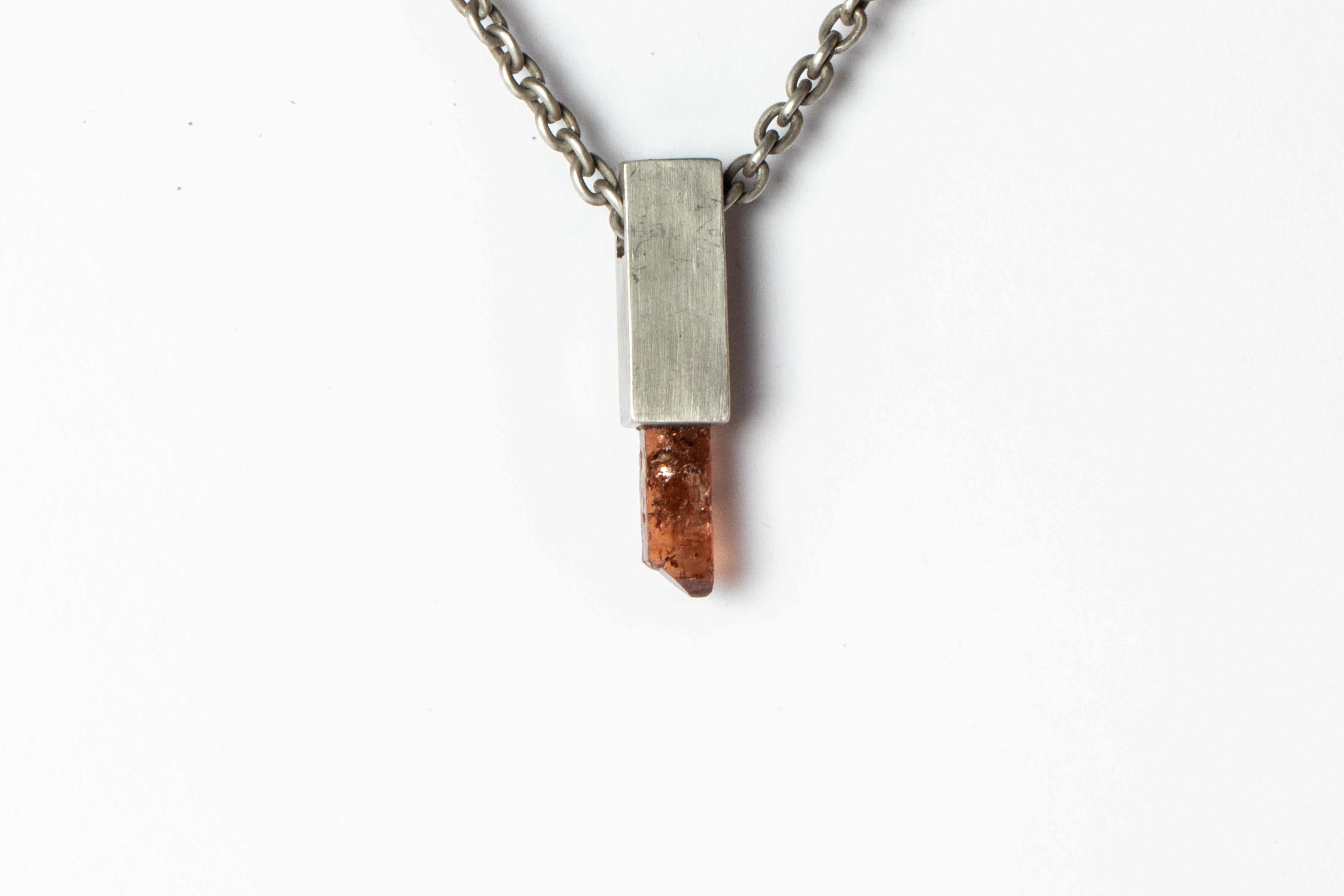 Pendant necklace in the cuboid shape made in dirty sterling silver and a rough of zircon. It comes on 74 cm sterling silver chain.
The Talisman series is an exploration into the power of natural crystals. The crystals used in these pieces are