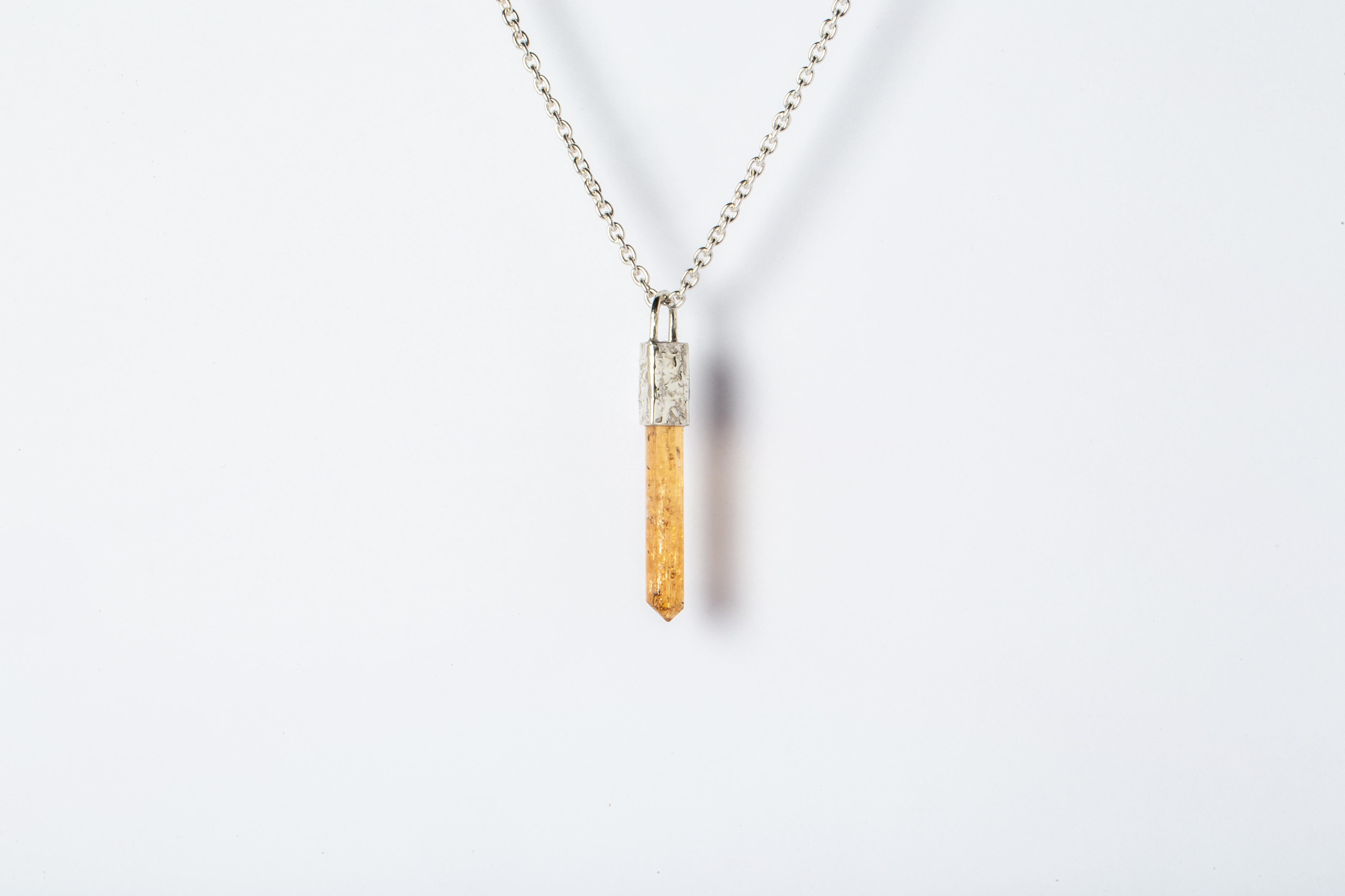 Talisman necklace in matte sterling silver with fused layer of 10k white gold and slab of rough imperial topaz. The Talisman series is an exploration into the power of natural crystals. The crystals used in these pieces are discovered through