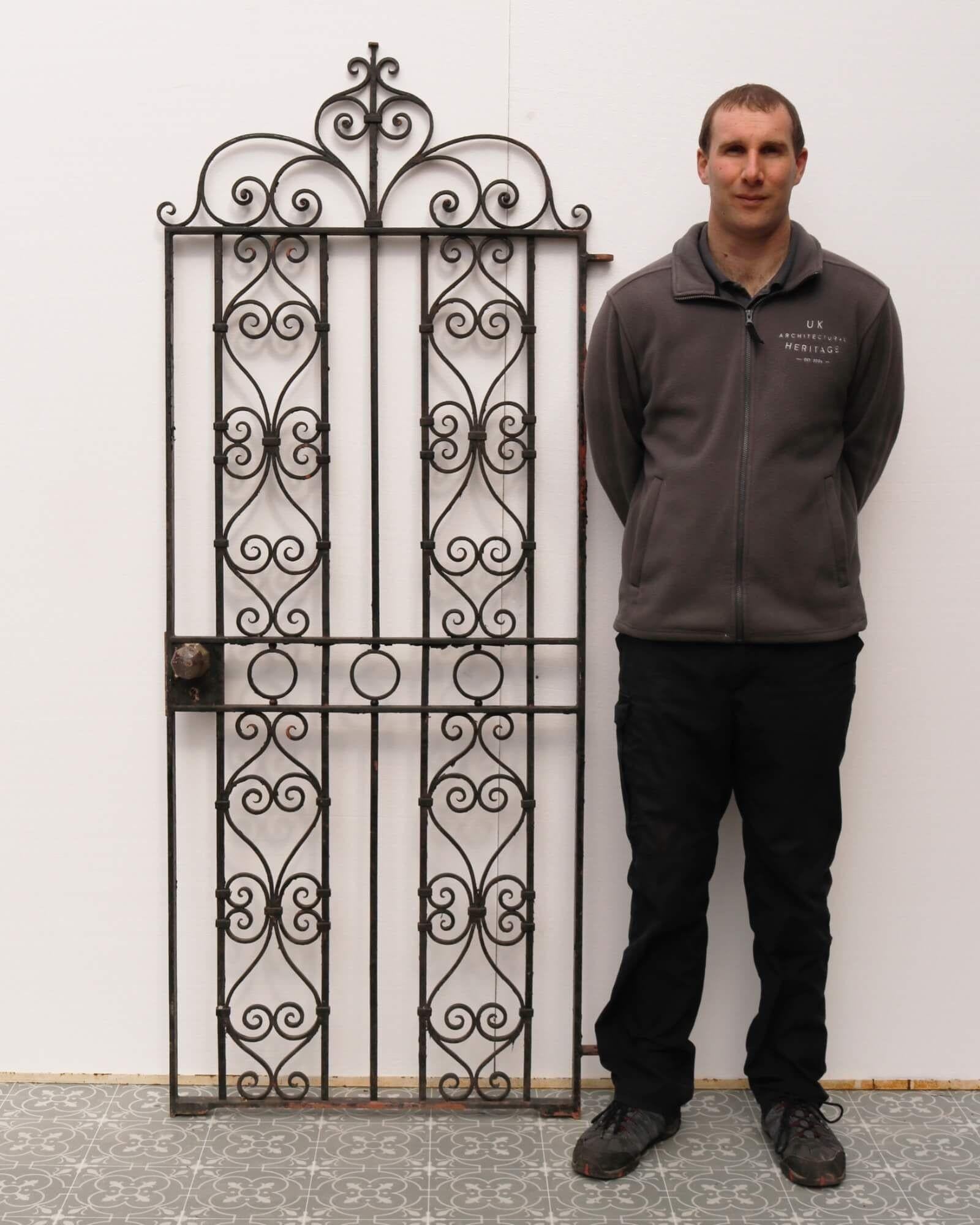 A tall and elegant 1930s wrought iron garden gate, perfectly proportioned for placement along the side of a house or for security in a narrow passageway. This tall Edwardian style gate is beautifully made with scrolling details throughout and a