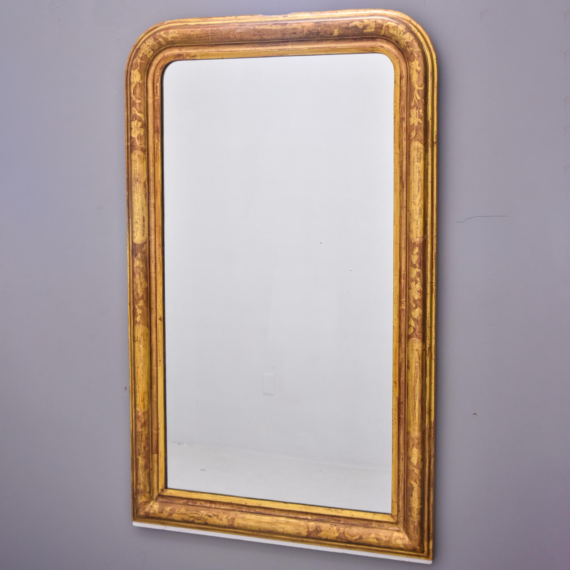 Found in France, this gilt wood Louis Philippe frame dates from approximately 1860s. Newer mirror. Frame has subtle etched pattern of flowers and leaves on a vine. Gilding is a warm gold with a red undertone. Very good antique condition with minor