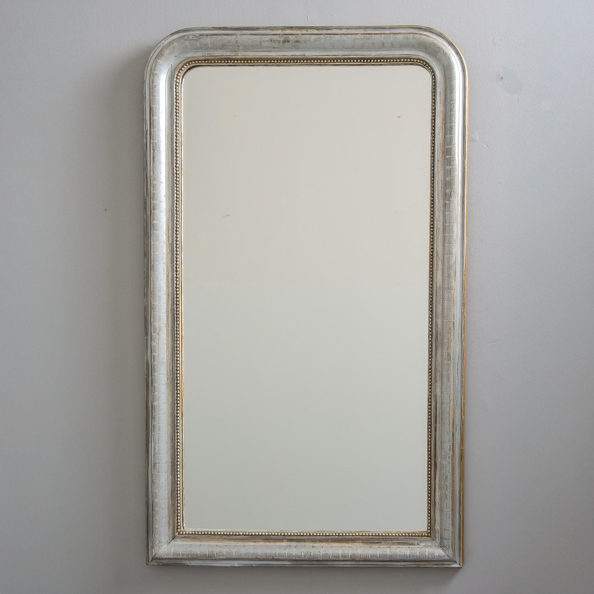 Found in France, this frame for this Louis Philippe mirror dates from the 1870s. The frame features a silver leaf finish, a subtle etched barred design and beaded inner edge. Actual mirror is newer and doesn’t appear to be original.  
Actual Mirror