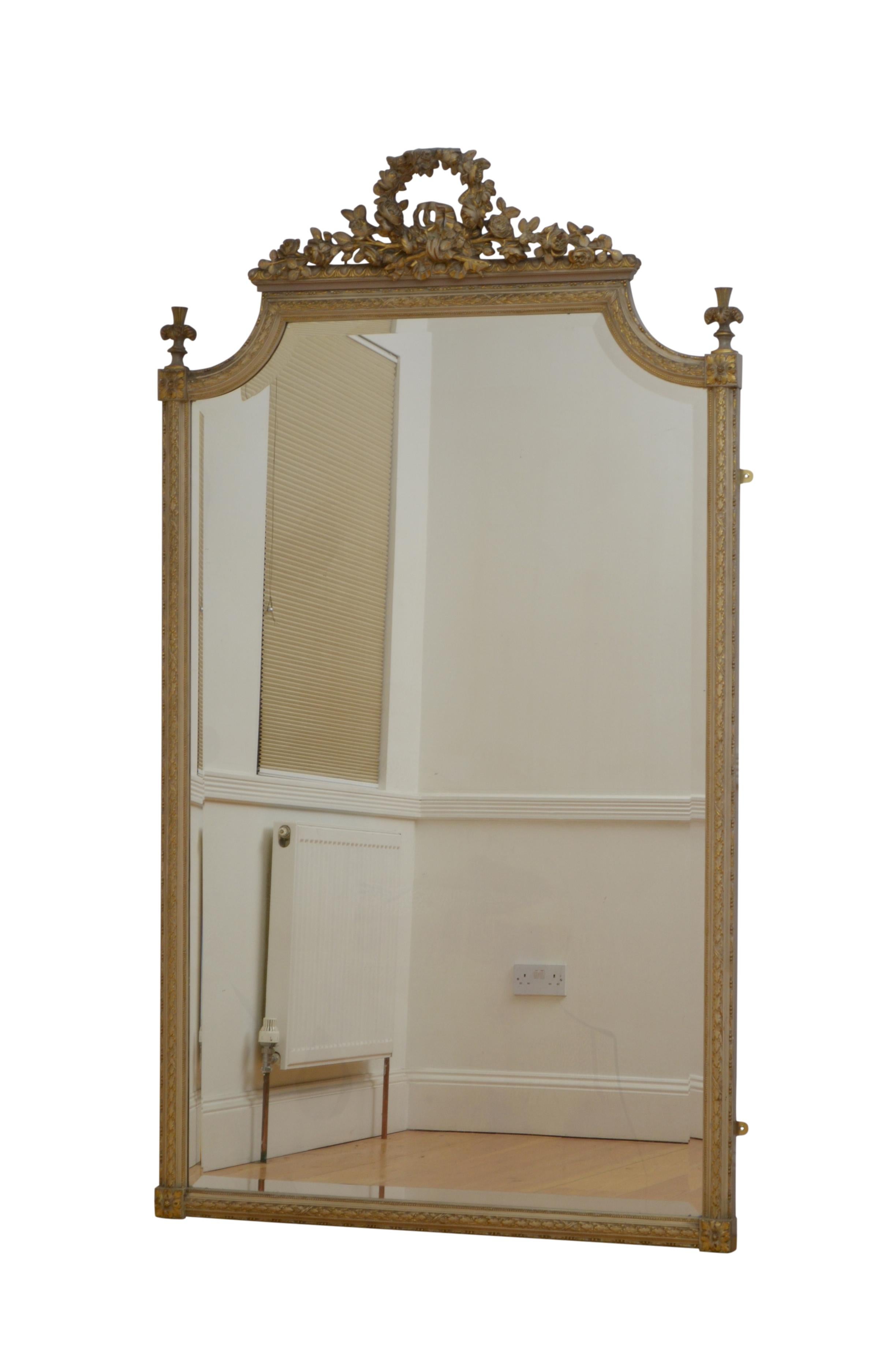 Superb 19th century leaner mirror or wall mirror, having original bevelled edge glass with minor foxing in moulded and carved painted and gilded frame with laurel leaf decoration and extensive floral crest in the shape of a wreath flanked by