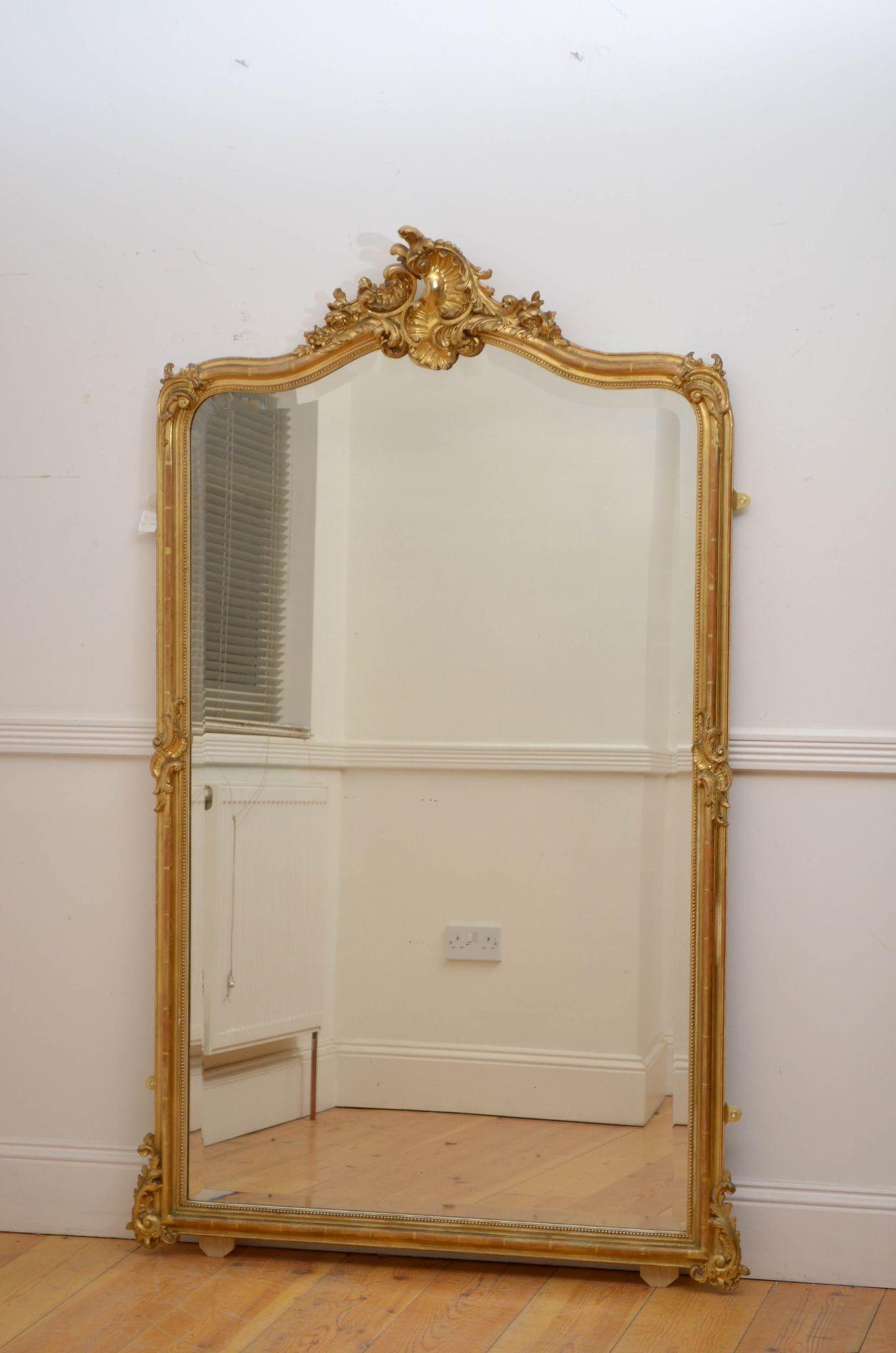 Sn5371 Specchio da parete in legno dorato francese del XIX secolo, con lastra originale dai bordi smussati con lievi imperfezioni, cornice dorata e modanata con volute d'acanto agli angoli superiori e stemma a conchiglia affiancato da motivi