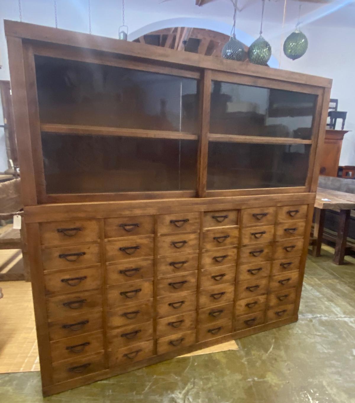 This cabinet is Japanese, Taisho to early Showa period (1920s-1930s). It has original wavy glass in its sliding glass doors in the upper portion of the cabinet, which was used for display, and has a shelf.
The lower portion is made up of 42 perfect