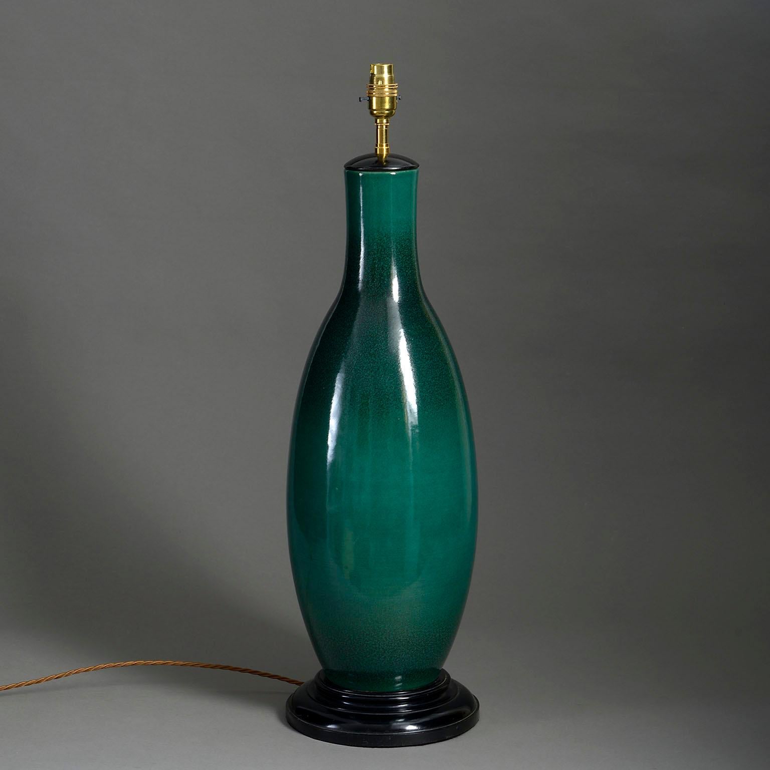 A tall mid-twentieth century deep green glazed vase of elongated bottle form, mounted upon a turned ebonised base as a table lamp.

Dimensions refer to vase and ebonised base only.

Wired to UK standards. This vase can be rewired to all