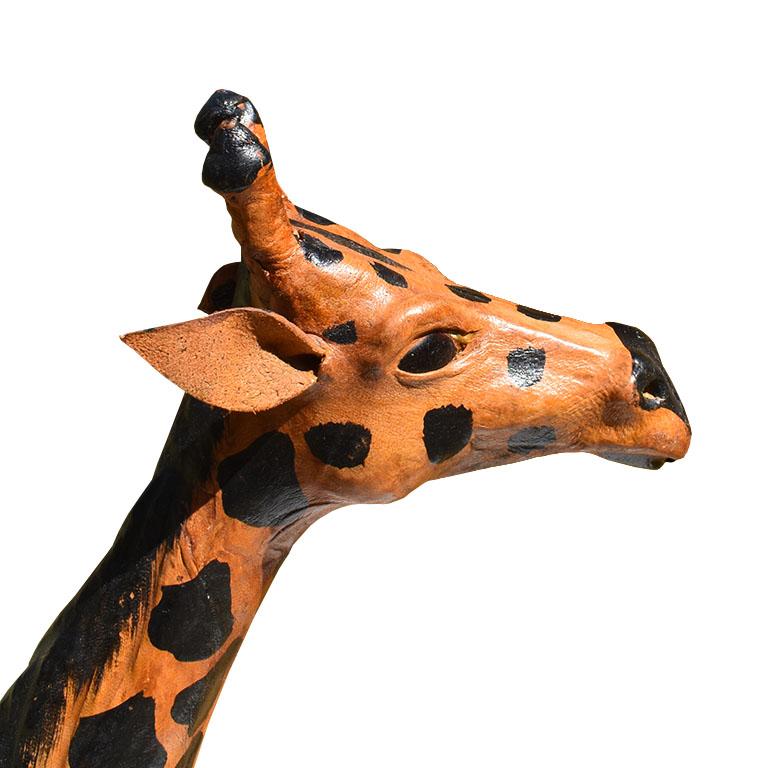 Une grande girafe en papier mâché de couleur noire et marron avec des oreilles en cuir et des yeux en verre. Nous voyons cette pièce amusante dans une chambre d'enfant ou dans un foyer. 

Mesures : 17.5