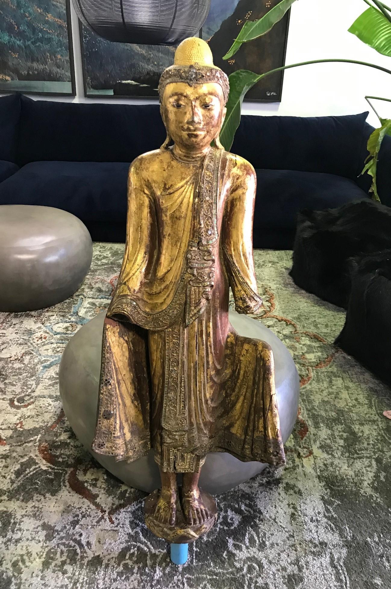 Tall hand carved wooden standing Buddha on a pole. Beautifully carved and finely detailed. Likely Thair or Burmese. Decorated with lacquer and gilt. 

Would be a great addition to any Asian art collection or eye-catching accent piece in about any