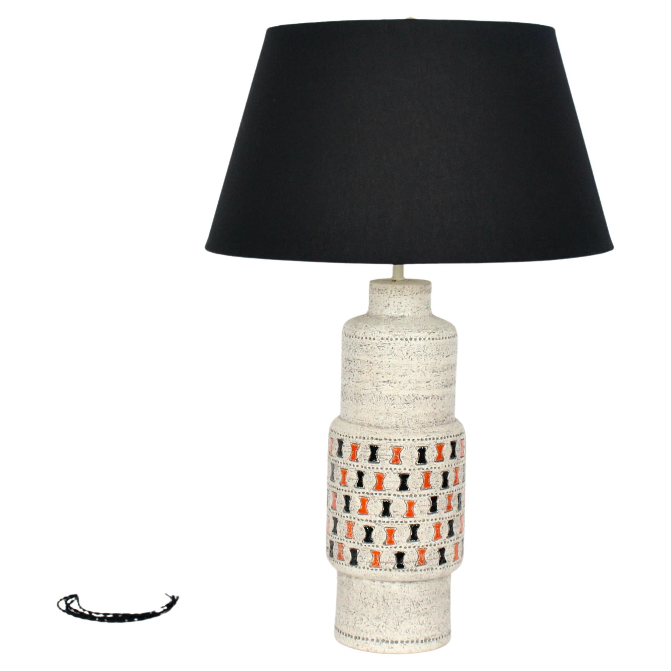Aldo Londi for Bitossi handcrafted off white art pottery table lamp, 1960's. Featuring a textured organic earthen form in Off White, Gray enhanced stipple, finished with hand painted Orange and Black abstract hourglass accents. Black shade shown for