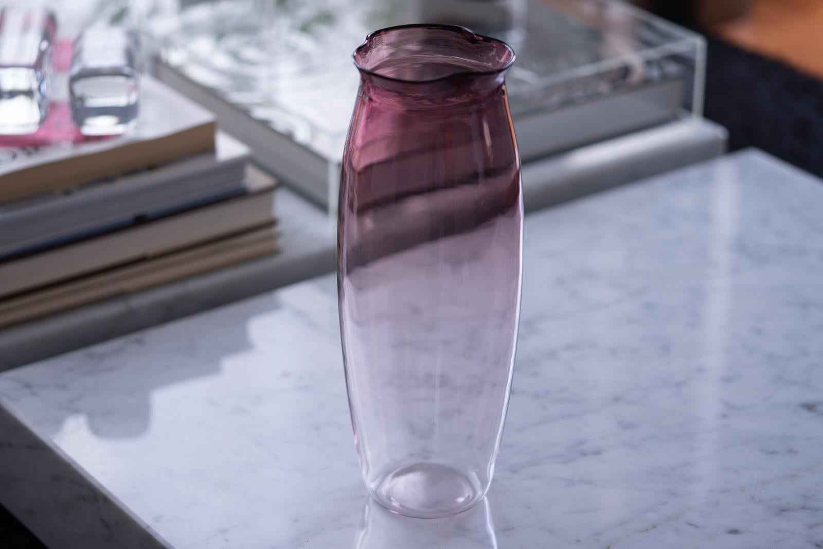 An elegant vase designed by Sergio Asti for Salviati in 2003. The thin blown glass walls gently curve and swell upward, transitioning from clear to violet at the top. Three pinched and rounded corners recall the form of the tulip flower from which
