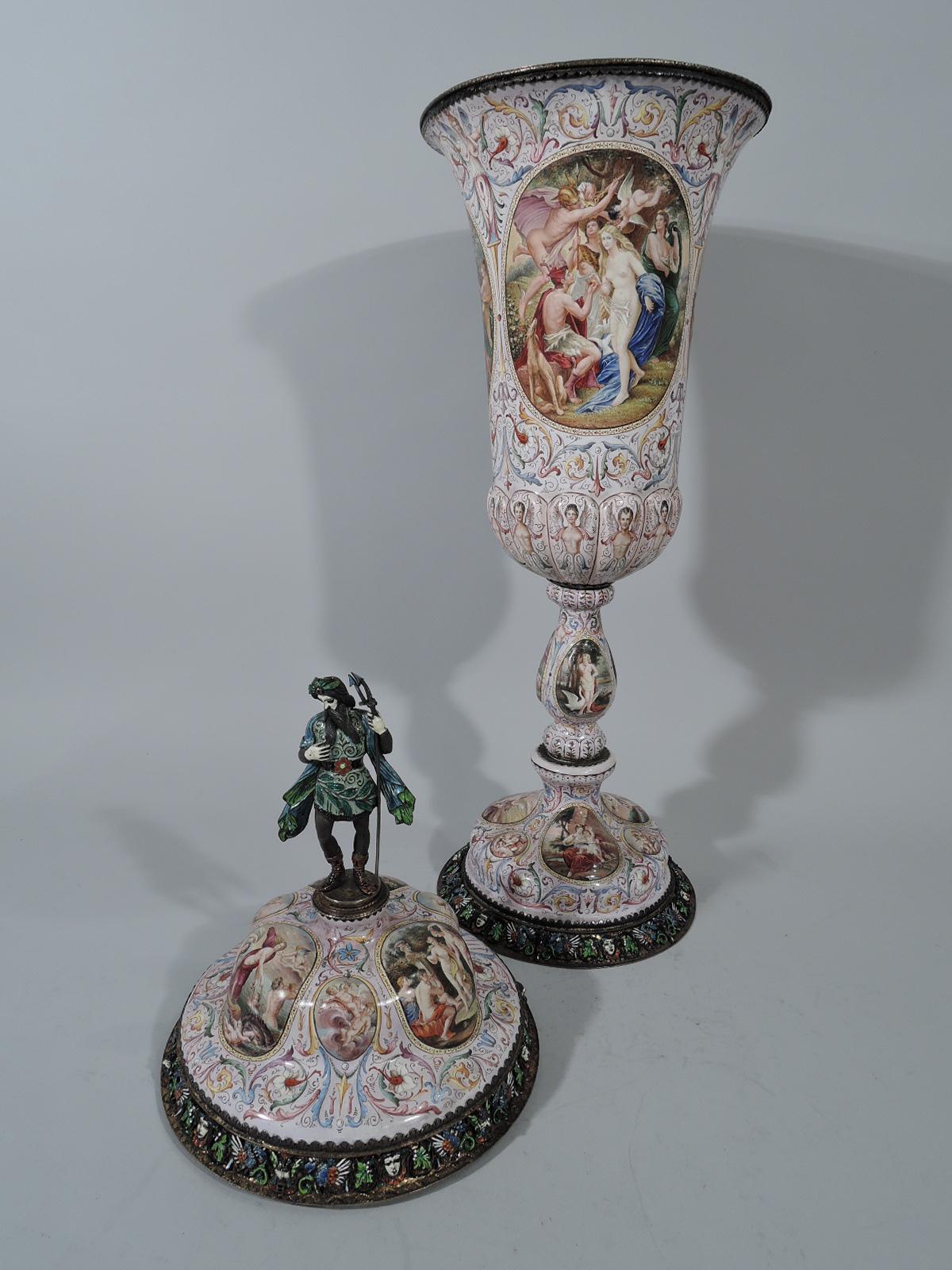 Tall classical Viennese enamel and silver covered cup, circa 1890. Tapering bowl with lobed vase on baluster stem on domed foot. Double-domed cover with figural finial in form of Neptune, a triton-holding bearded man in double and hose. Painted oval