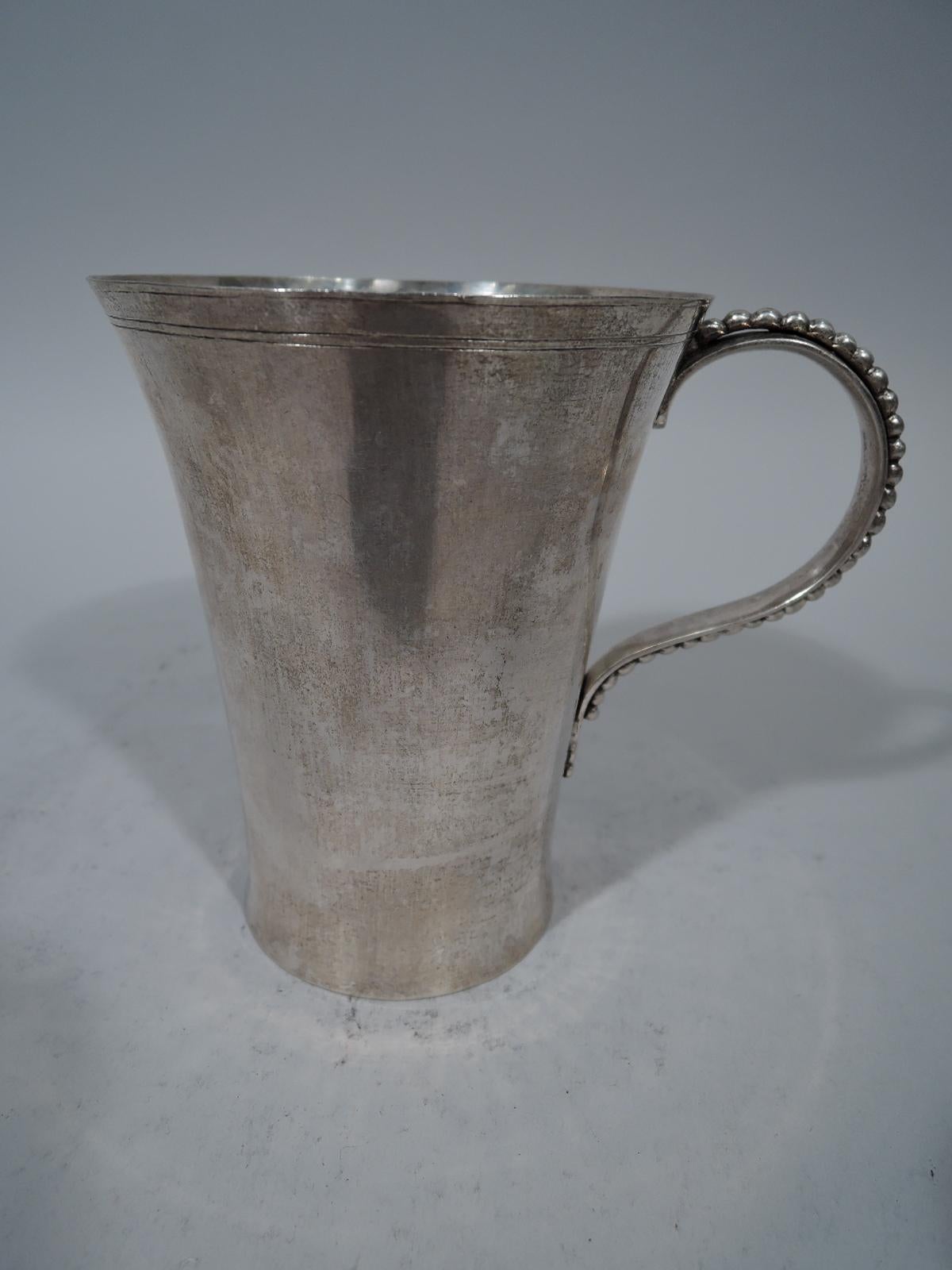 Tall and heavy South American silver mug, circa 1860. Tapering with finely engraved rim bands. Scroll handle applied with beading. Interior has visible signs of handwork. Weight: 10.5 troy ounces.