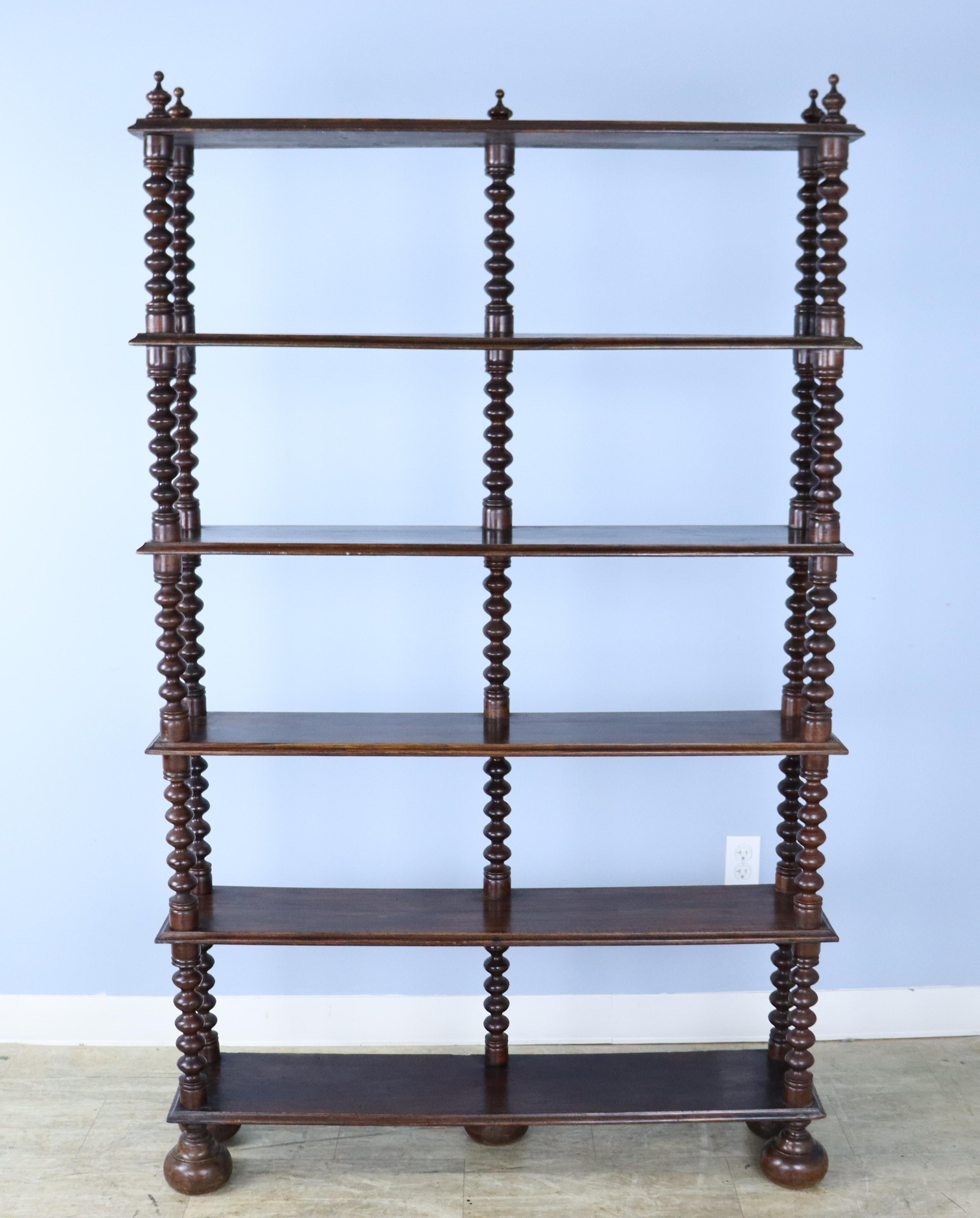 A tall bookshelf with eye catching turned supports. A beautiful look and shallow enough to hold paperbacks or art objects without imposing on the space. Quite stable and can stand on its own or against the wall. Charming bun feet. If you want the