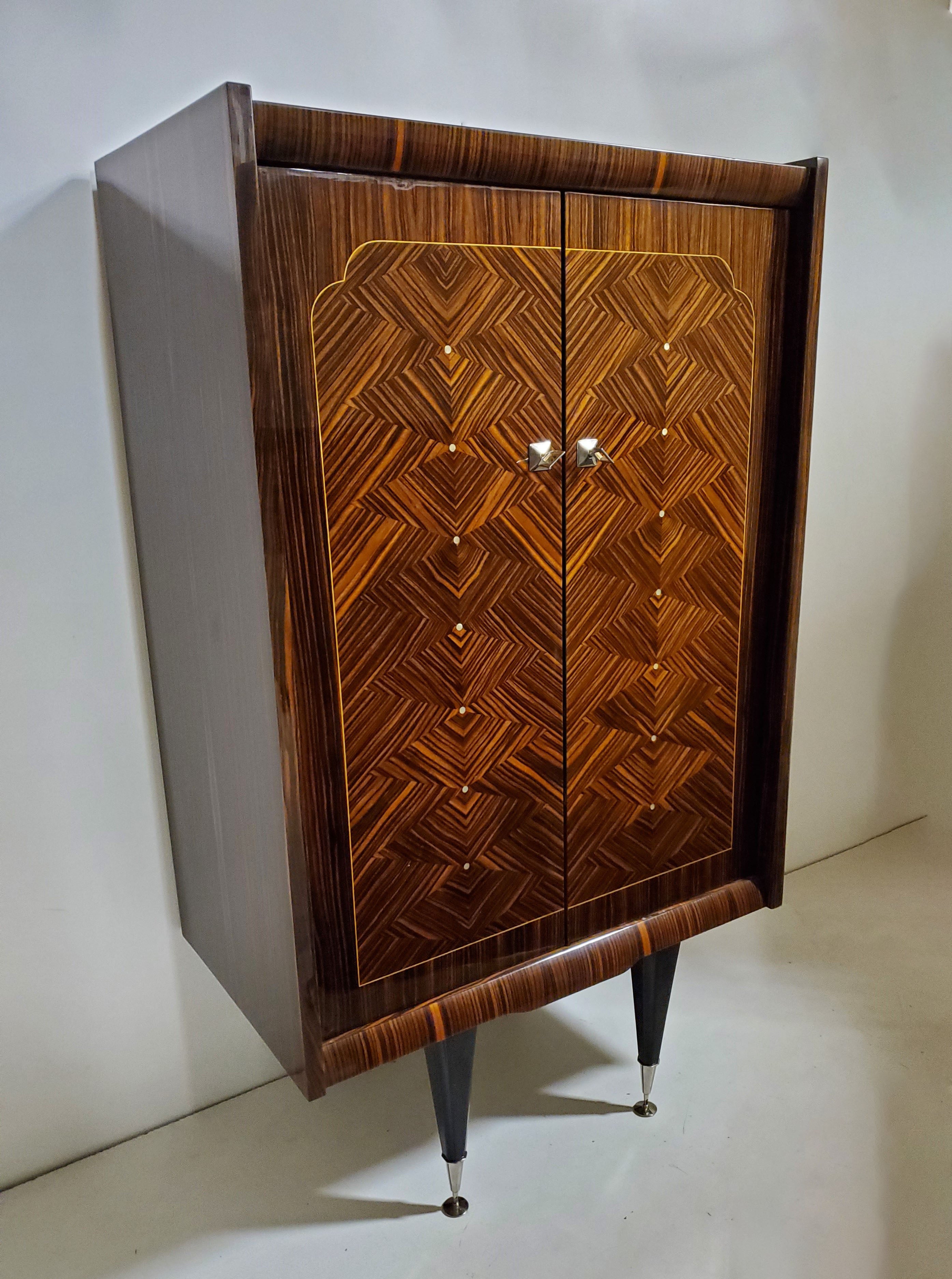 An outstanding French Art Deco / Mid Century Modern tall cabinet.
with N.F. Ameublement seal. The armoire features stunning Macassar ebony in a geometric parquetry inlaid pattern with dots of decorative mother of pearl inlay. The case rests on