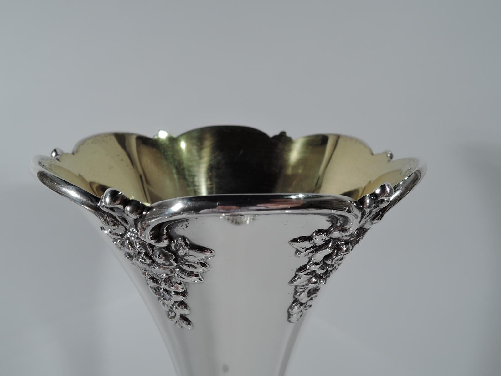 Tall and unusual sterling silver vase. Made by Tiffany & Co. in New York. Attenuated oval body with soft fluting on lobed and domed foot mounted to circular base with four foliate-shell supports. Neck and mouth conical with scalloped rim and applied