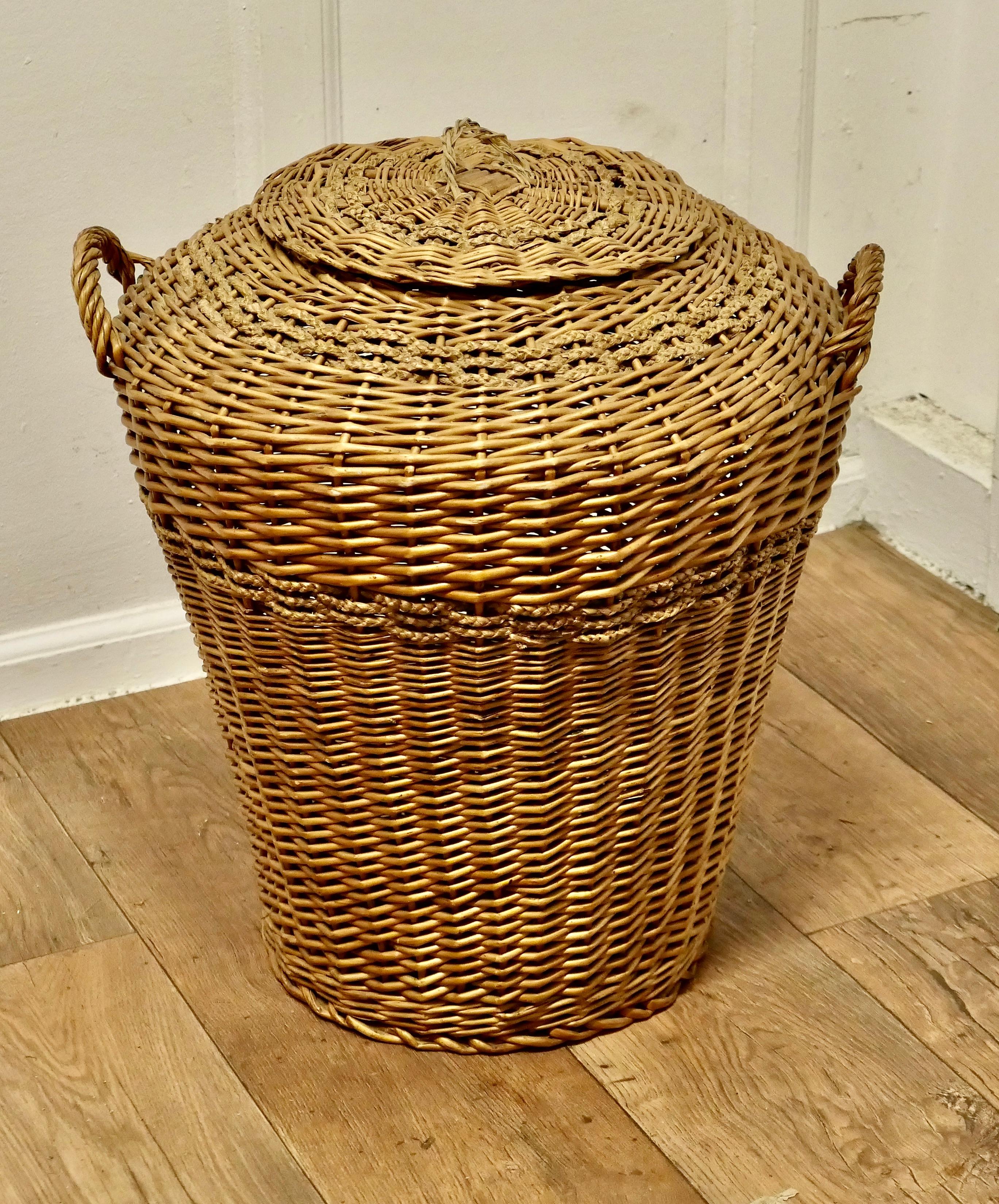 Tall Antique Ali Baba Wicker Laundry Basket

This is an excellent example and in remarkably good condition for its age, the basket is round, tall with strong carrying handles and a lid.
It is woven in age darkened Willow and decorative sea grass