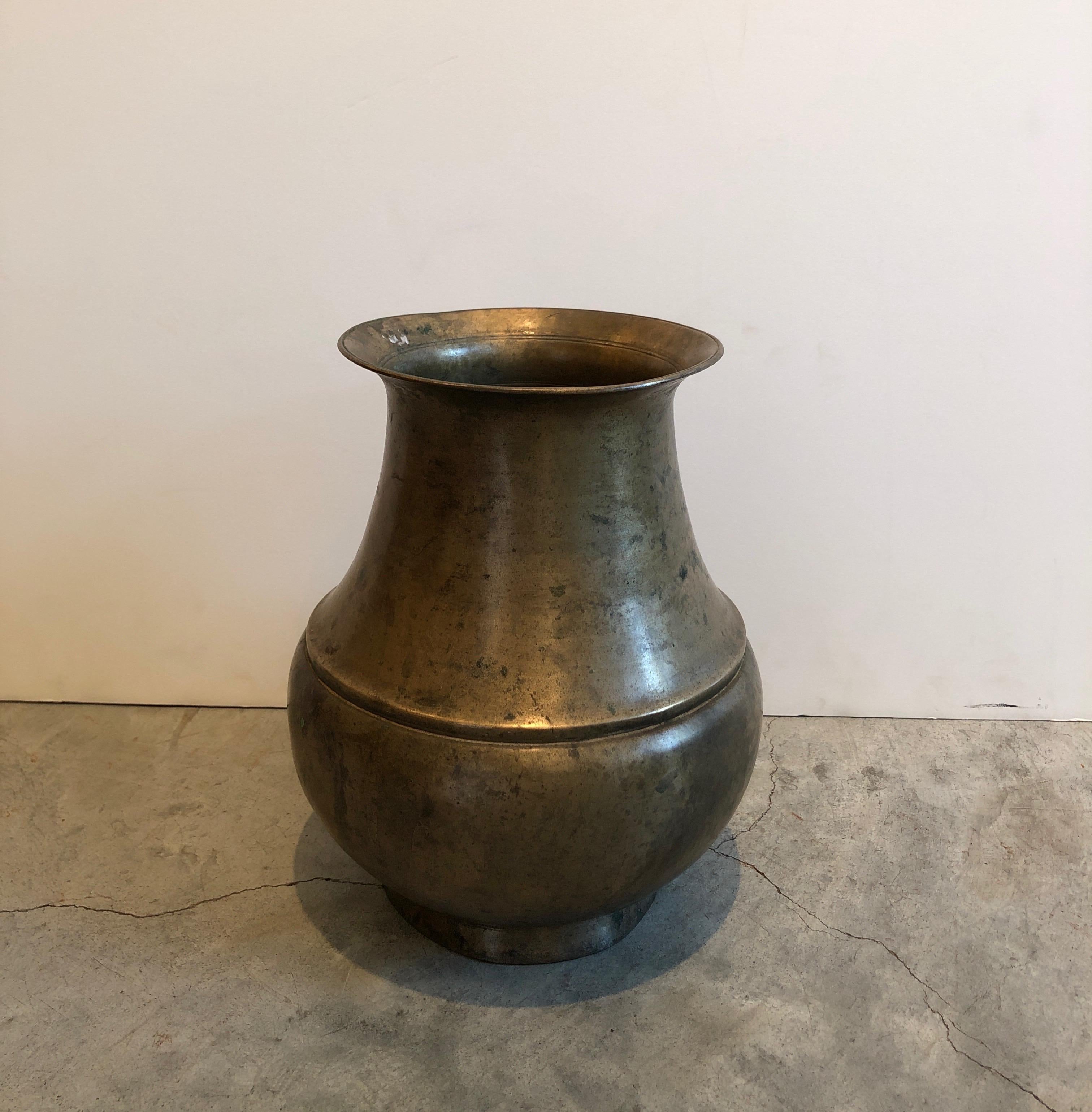 A perfectly patinated, tall and heavy bronze antique Tibetan holy water container. It's graceful shape, simple lines and fine casting add beauty and presence to this spiritual piece. A wonderful object that will add interest in any room.