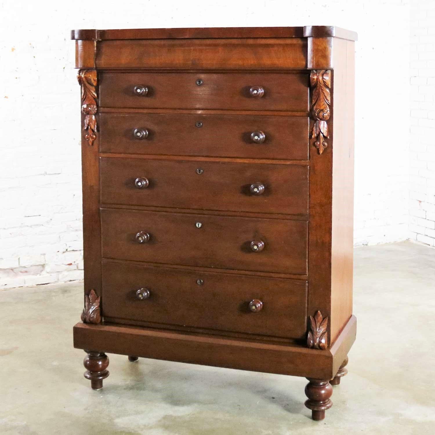 Handsome, very useful, and very tall antique Edwardian chest of drawers in pine with burl wood veneer front, most likely walnut; mother of pearl inlay on knobs; and carved acanthus leaves. It is in good antique condition with lots of patina. It