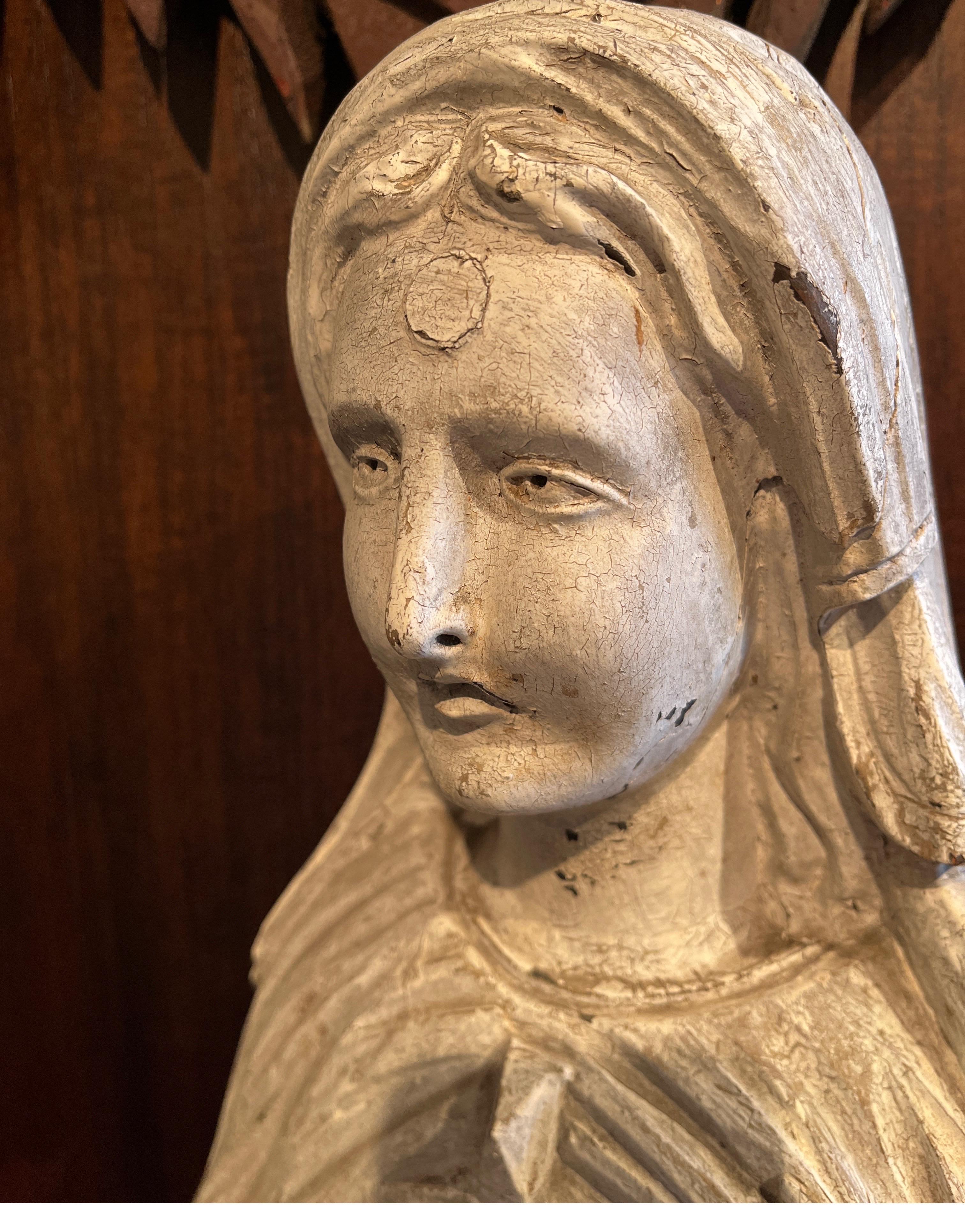 Eine große, feinfühlig geschnitzte antike Holzfigur der Madonna.  Das fast einen Meter hohe, kunstvoll geschnitzte Gesicht Marias, umgeben von anmutig fließenden Gewändern und einer Kopfbedeckung, vermittelt ein fast unbeschreibliches Gefühl von
