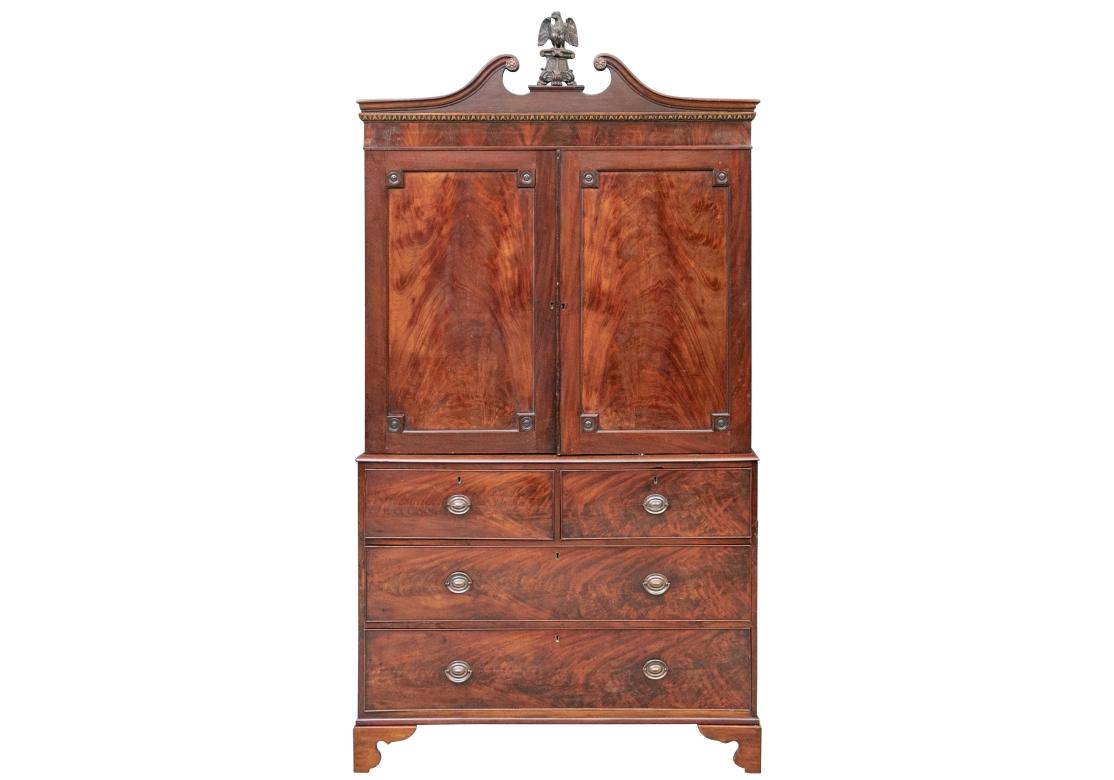 Quality craftsmanship with a broken bonnet and fine carved eagle with spread wings standing on a tripod pedestal for the finial. Two top doors open to one custom later made adjustable shelf (with a hole in back for an entertainment unit). Lacking a