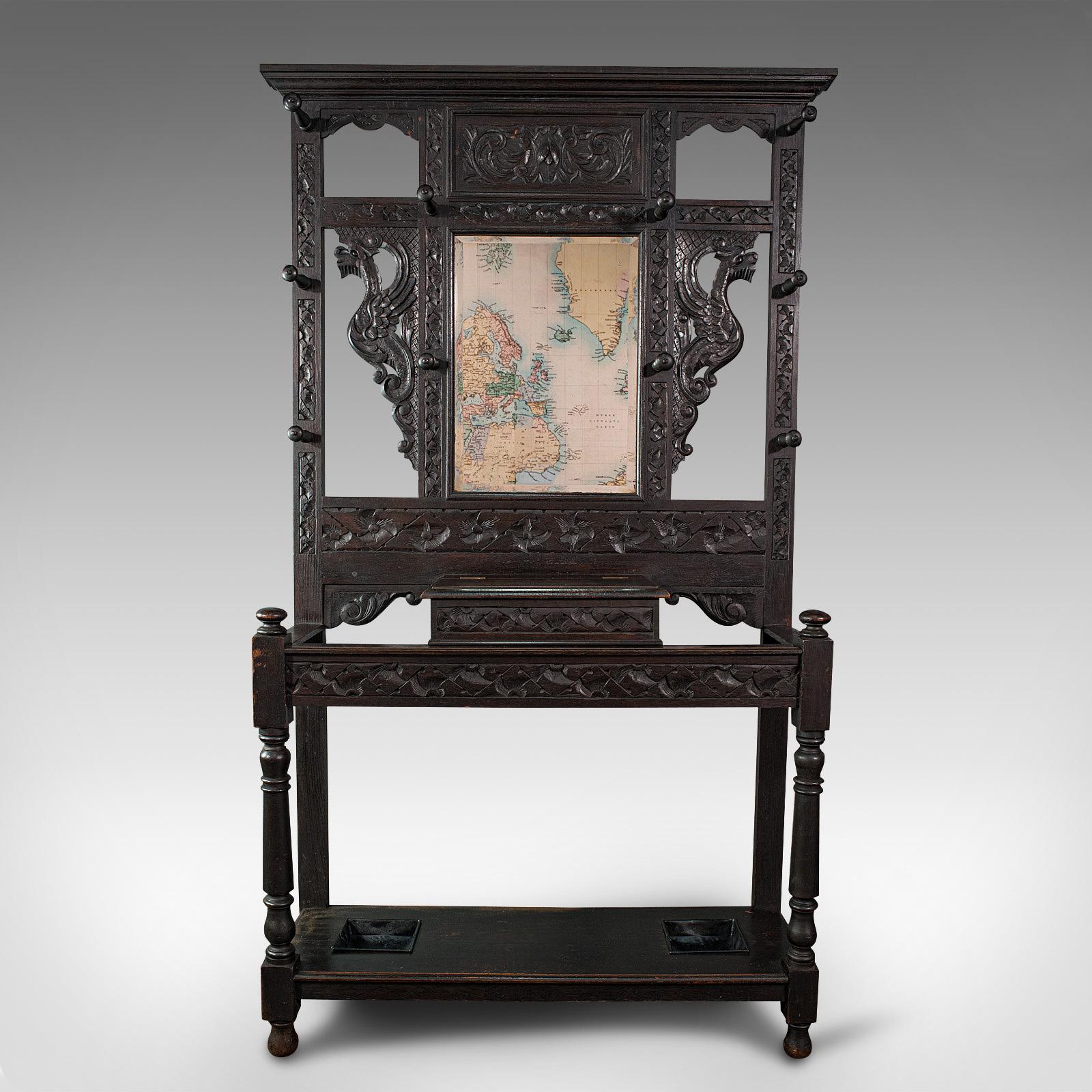 This is a tall antique hall stand. An English, oak stand with mirror and coat rack of carved Chinoiserie taste, dating to the Victorian period, circa 1880.

Distinctive Oriental carvings decorate this versatile stand
Displays a desirable aged