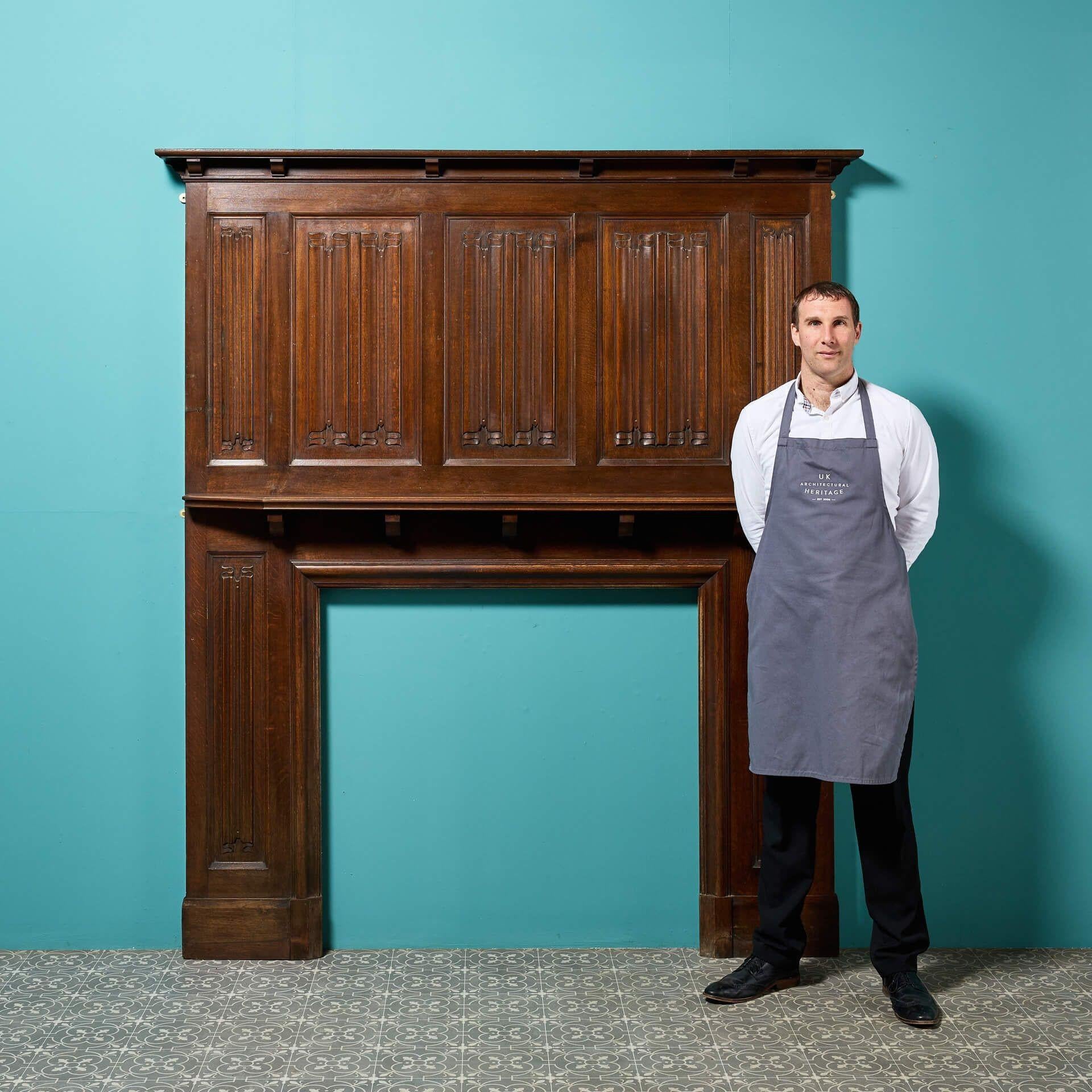 A tall antique Jacobean style carved oak fireplace with an impressive linen fold panelled overmantel.

Striking in style and stature, this fireplace dates from the late 19th century but encompasses earlier Tudor and Jacobean revival styles