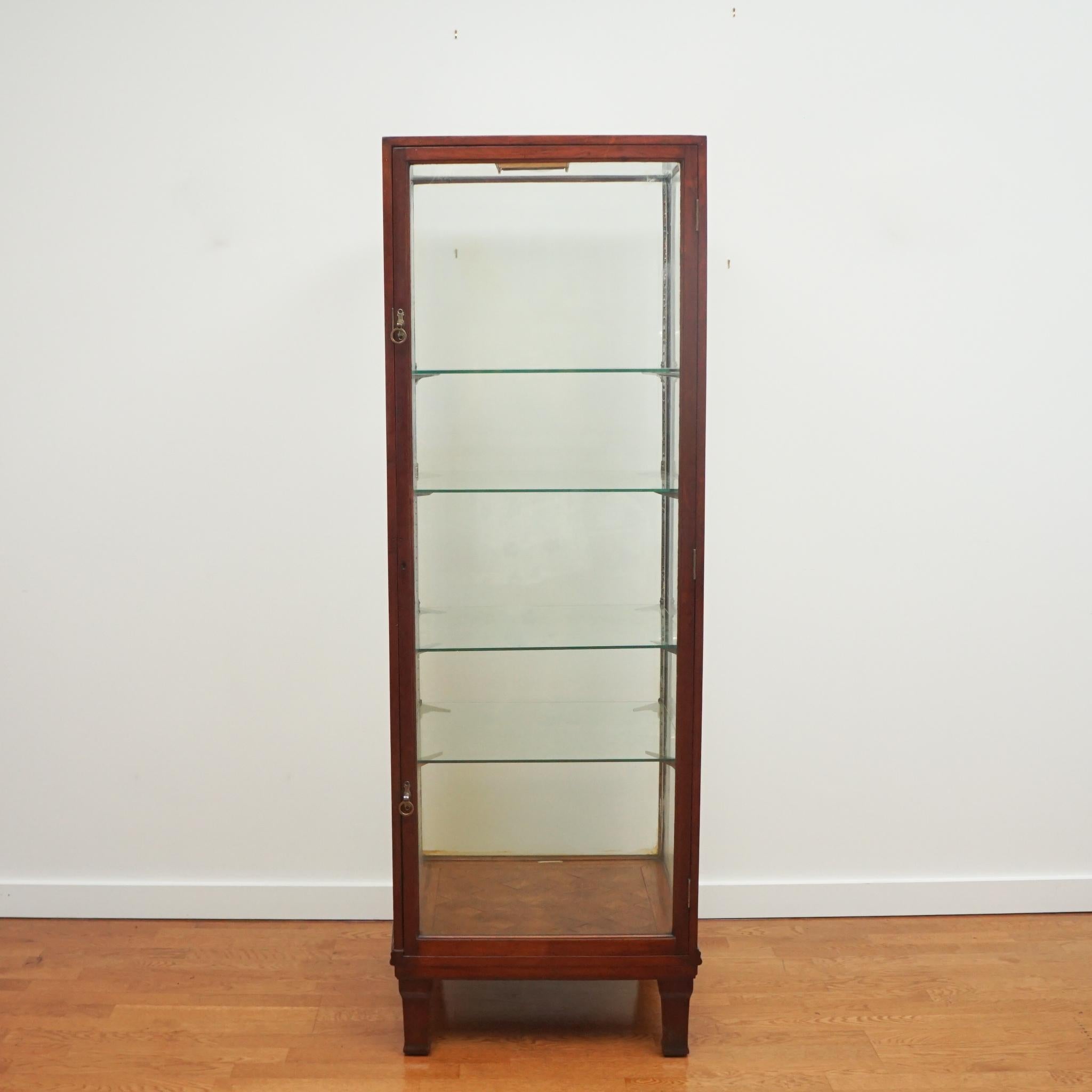 Even with its small footprint, this handsome tall mahogany display case offers plentiful storage for collectibles and objet d'art.  Marked 