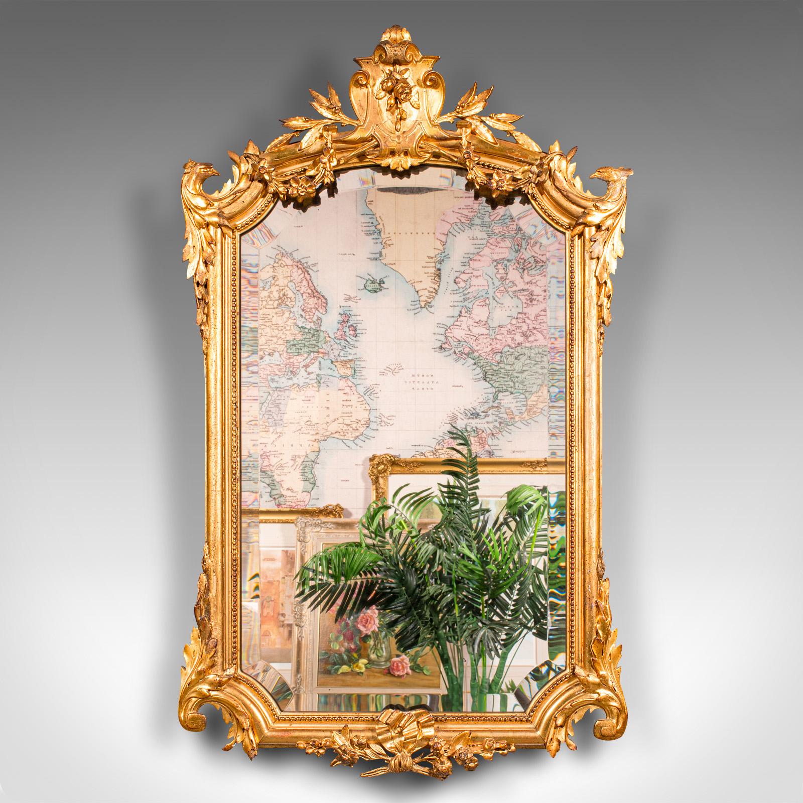 
This is a tall antique overmantle mirror. A German, giltwood bevelled wall mirror, dating to the late Victorian period, circa 1900.

Striking golden tonality with a generously sized mirror plate
Displaying a desirable aged patina with original