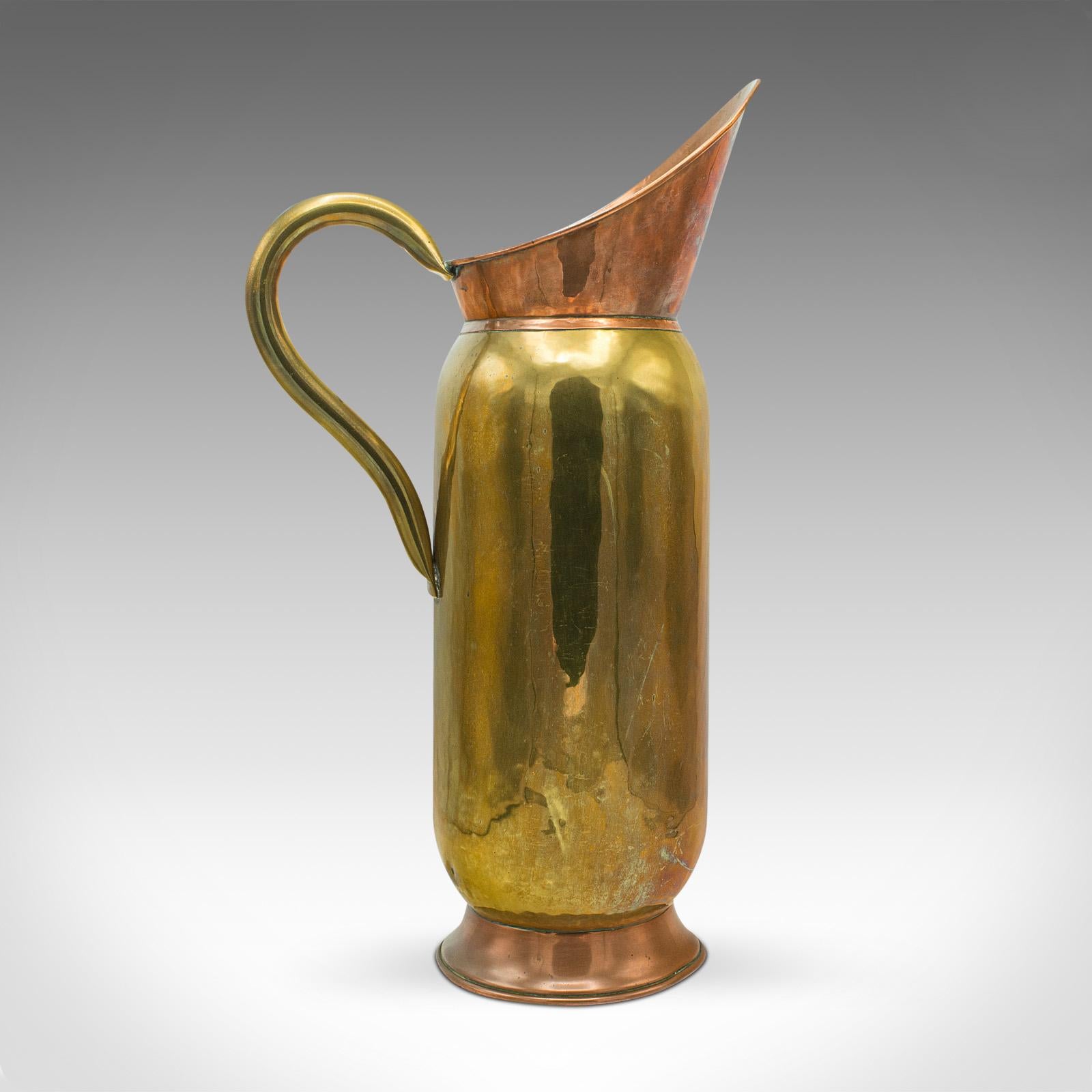 This is a tall antique pouring jug. An English, brass and copper ewer or long stem vase, dating to the late Victorian period, circa 1900.

Distinctive use of Dual materials creates an attractive appearance
Displaying a desirable aged patina and