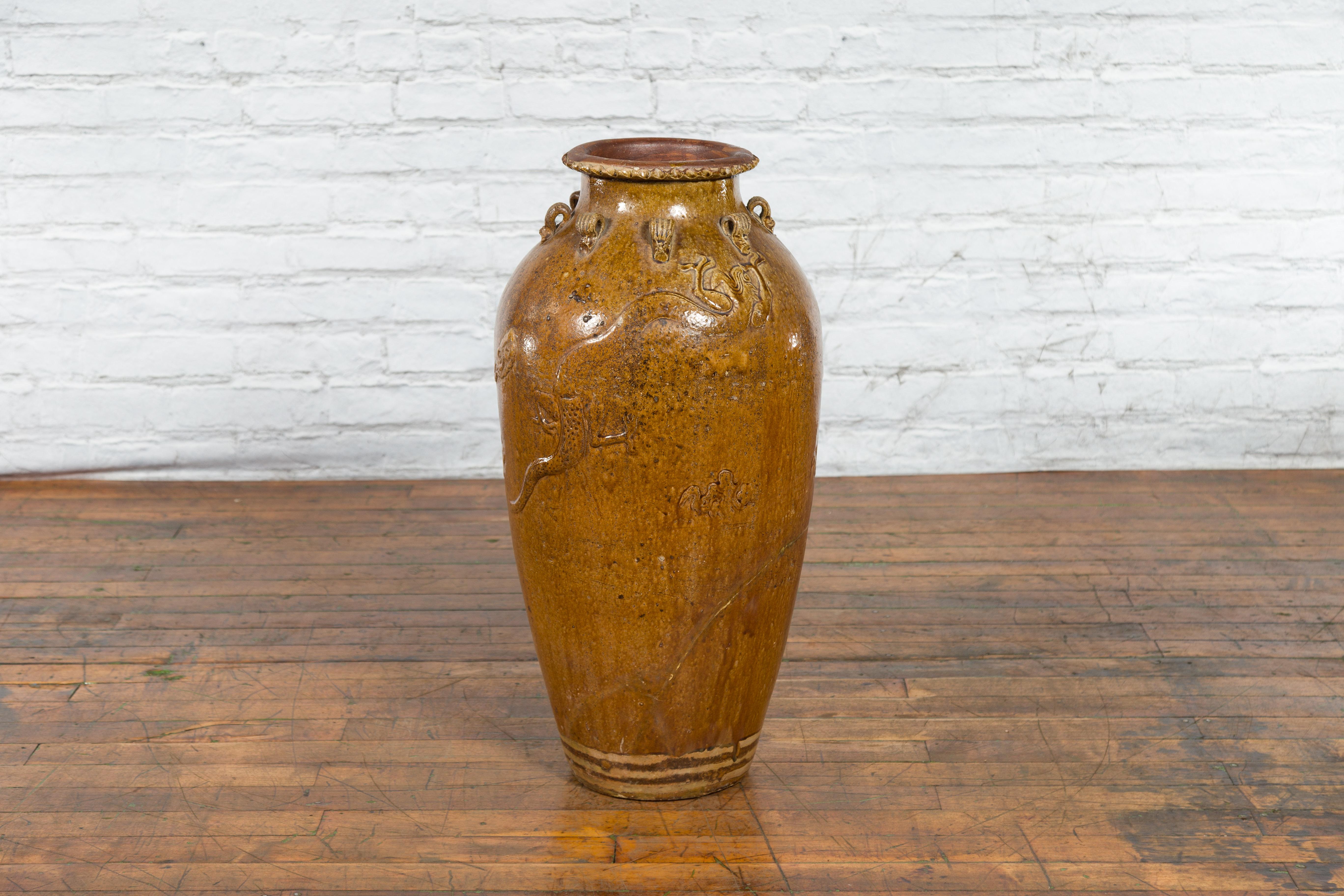 A Chinese Qing dynasty period Martaban jar from the 18th-19th century with dragon motifs and loop handles. This tall Chinese jar comes from the Martaban wares, where it was produced during the Qing dynasty (1636–1912). This tall jar is made of