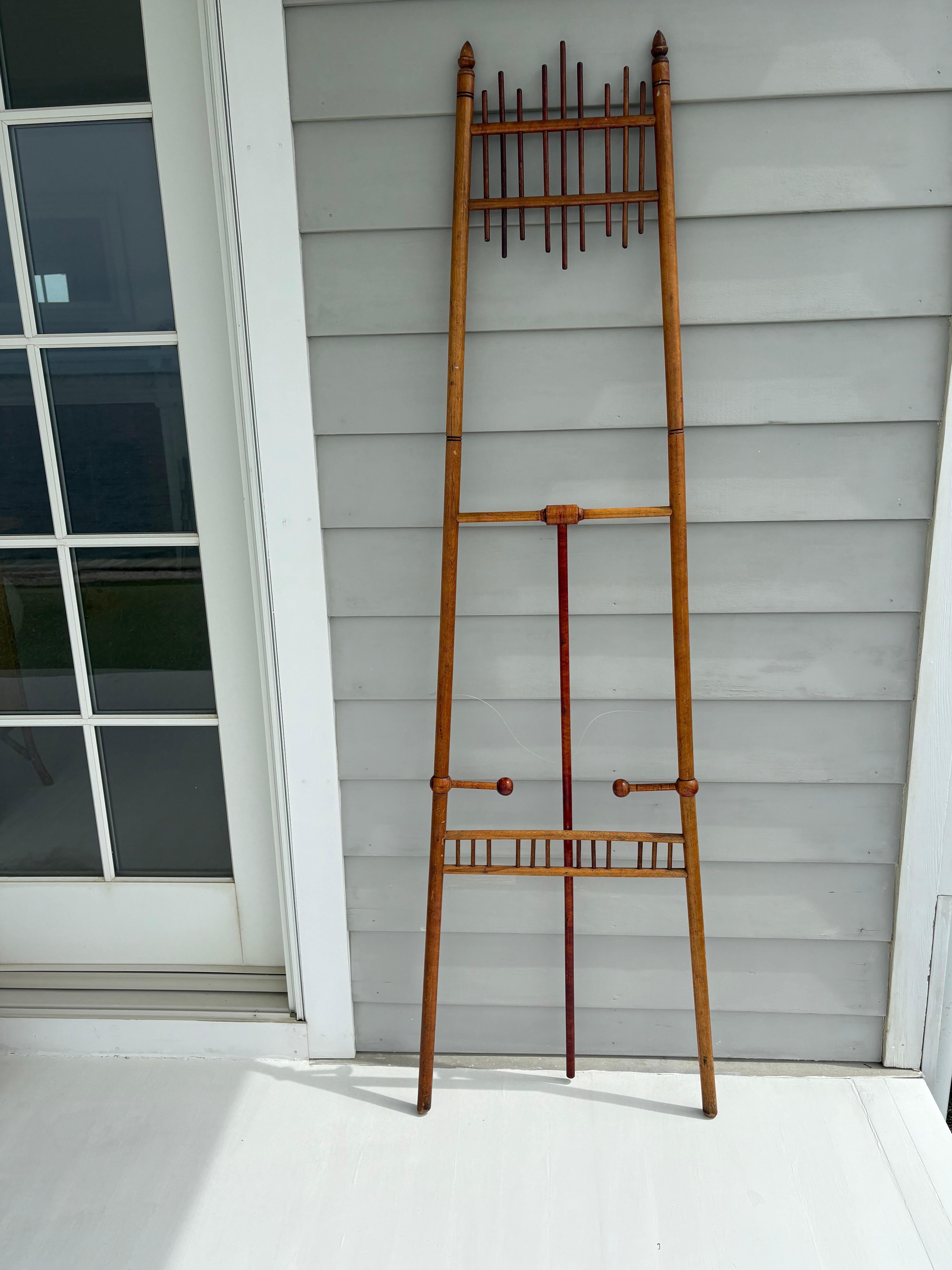 Caballete antiguo de palos y bolas muy sencillo y elegante . El caballete tiene 3 patas, 2 delante y 1 detrás que se sujetan con una cuerda de plástico para abrirse y cerrarse . Las patas delanteras tienen 2 palos de madera con bolas en los extremos