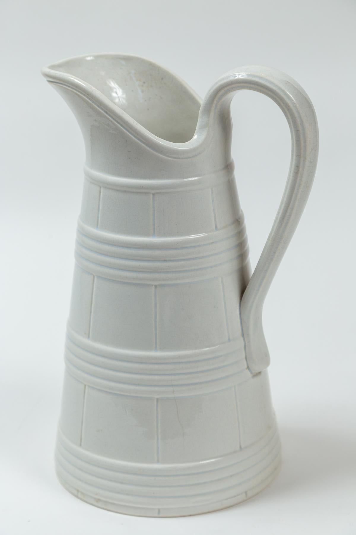 Cántaro alto de piedra ferruginosa blanca, Bélgica, hacia 1890. Jarra de gran tamaño con bandas en relieve y diseño impreso de imitación de bois, que evoca una jarra de madera. 
