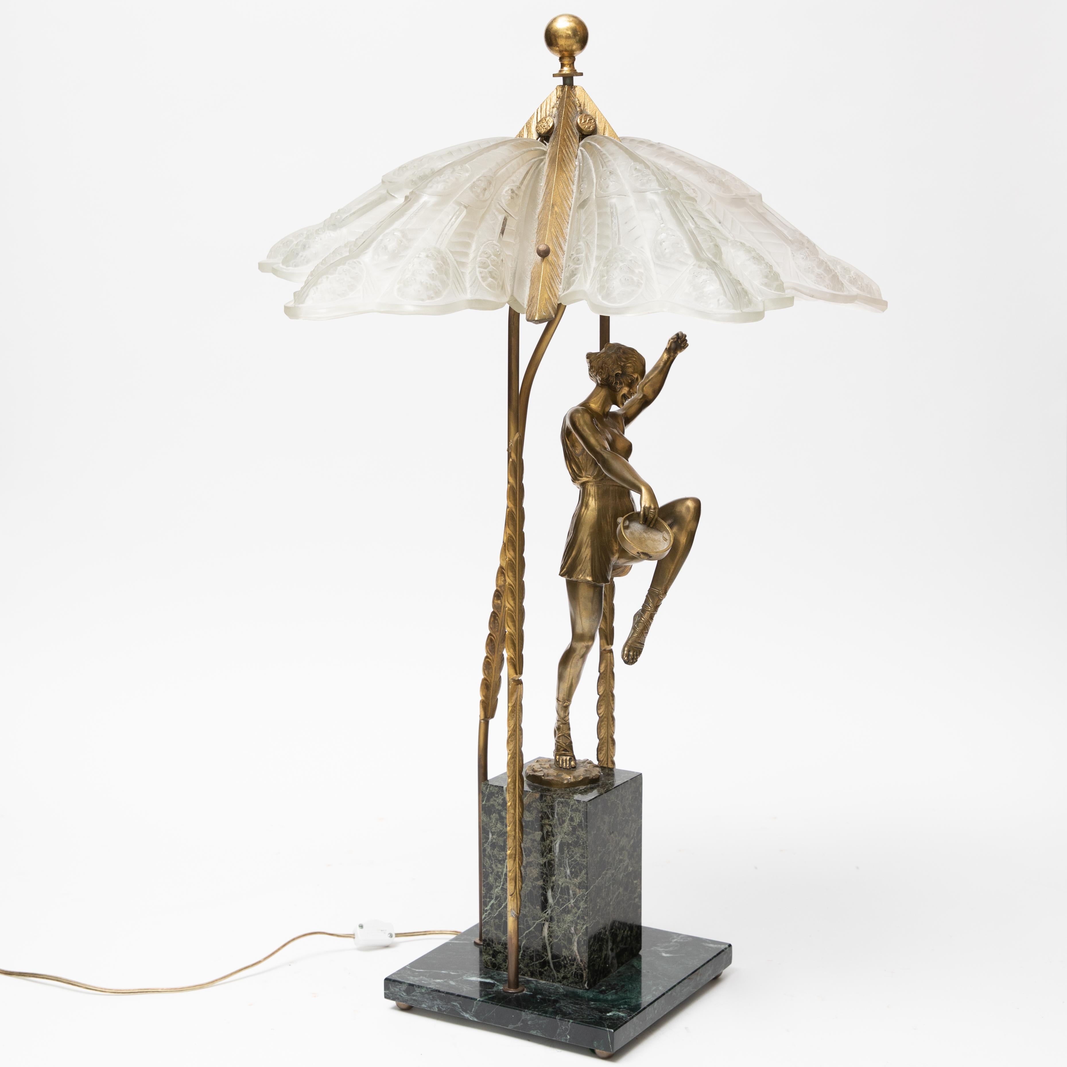 Tall Art Deco brass and frosted glass lamp. This lamps depicts a dancer holding a tambourine in her right hand. The glass shade resembles Lalique in style and is all held together with brass fittings on top of a marble base. This lamp measures 33.5