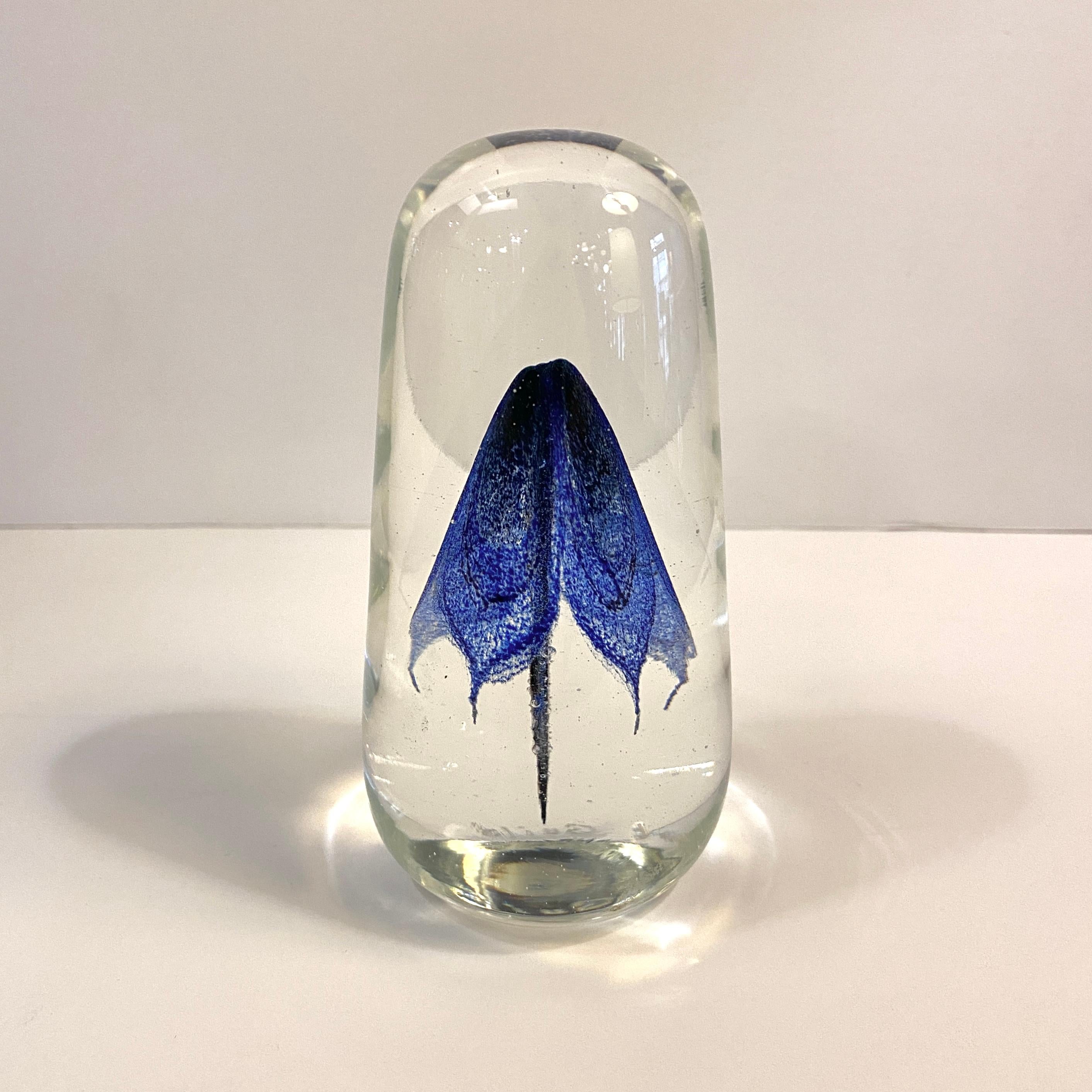 Artisan-made, hand-blown, art glass paperweight by Rochester Folk Art Guild features a graceful, cobalt blue form resembling a jellyfish or a flower encased in a clear glass tall oblong shape that tapers on top. Signed and dated 1983.  It's a